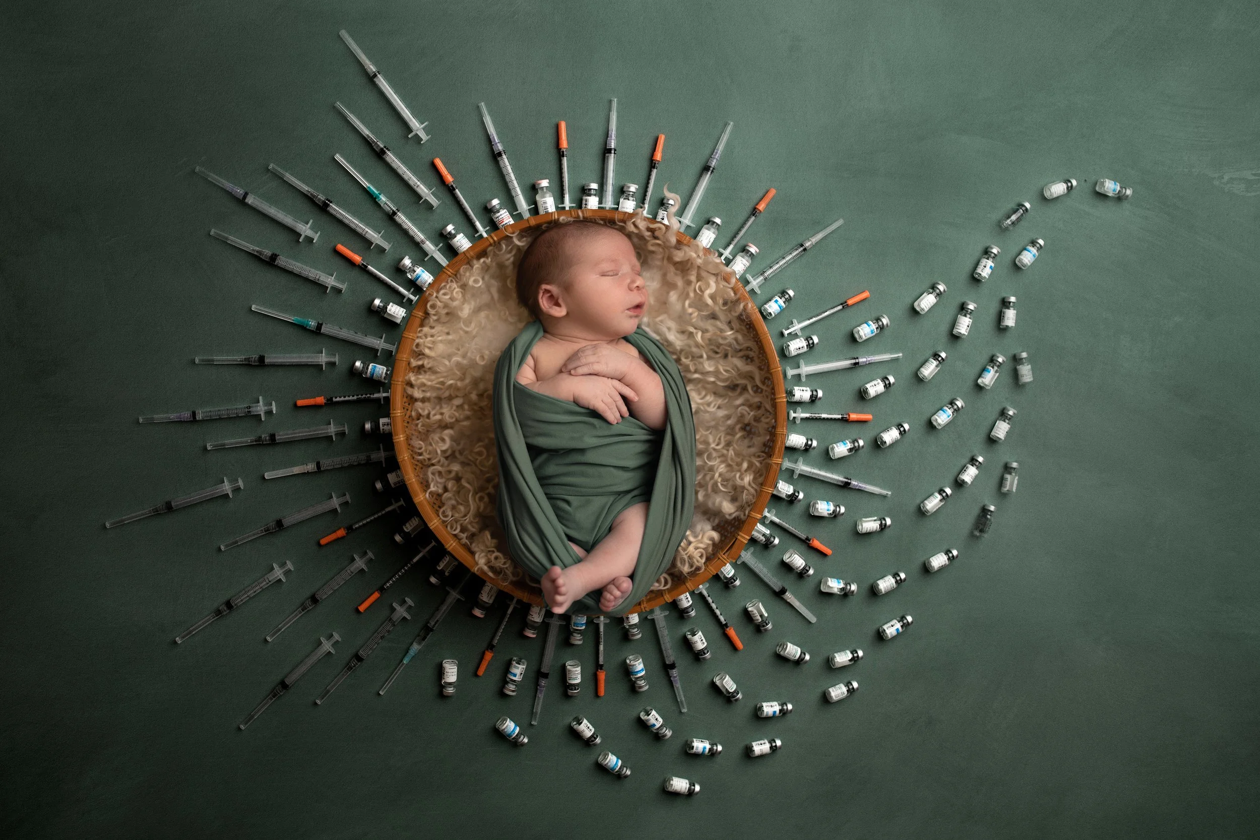 newborn baby surrounded by fertility syringes