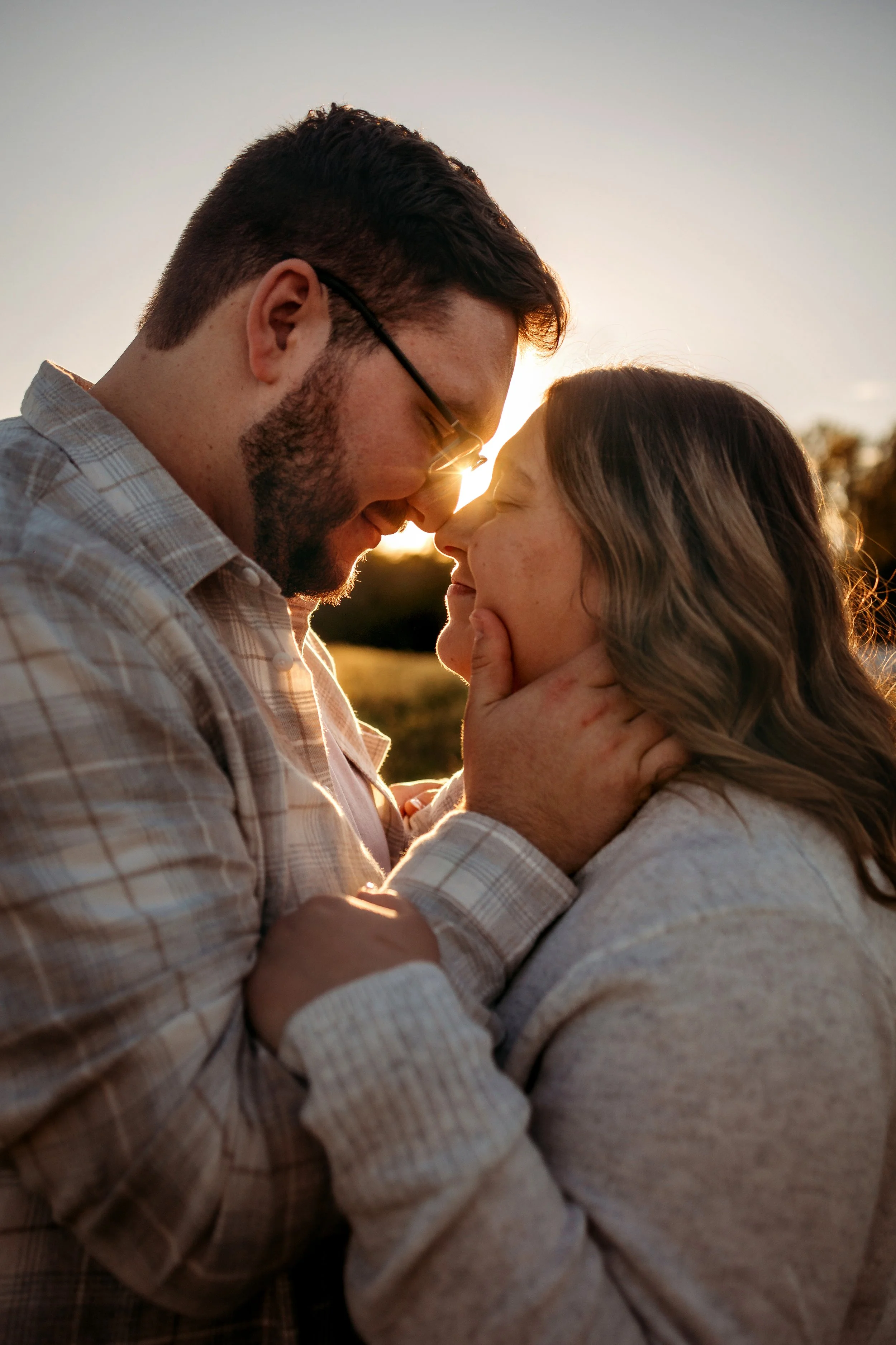 couple with foreheads and noses touching and sun spilling in between them
