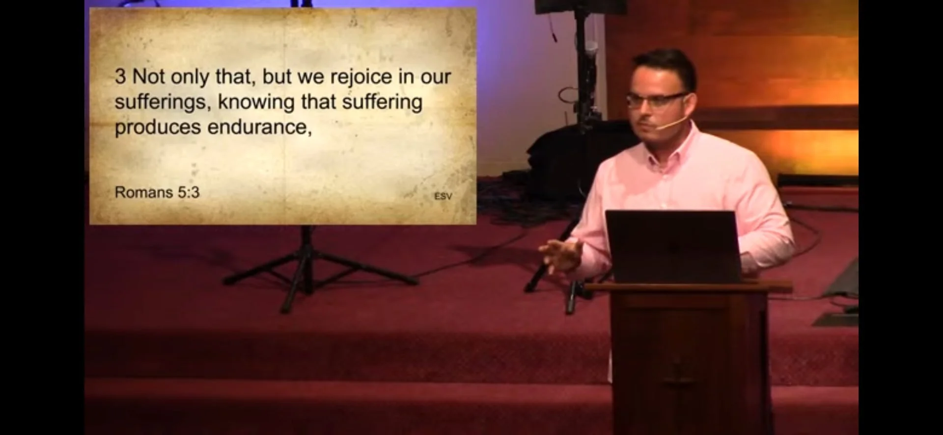 Pastor Brian Drummond teaching from Romans 5:3 during a church service.
