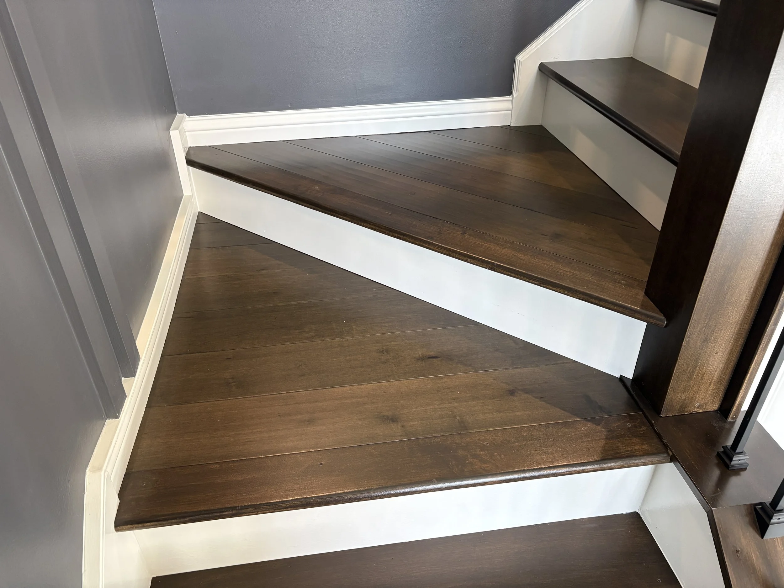 dark stained maple staircase in entryway with white risers and black balusters