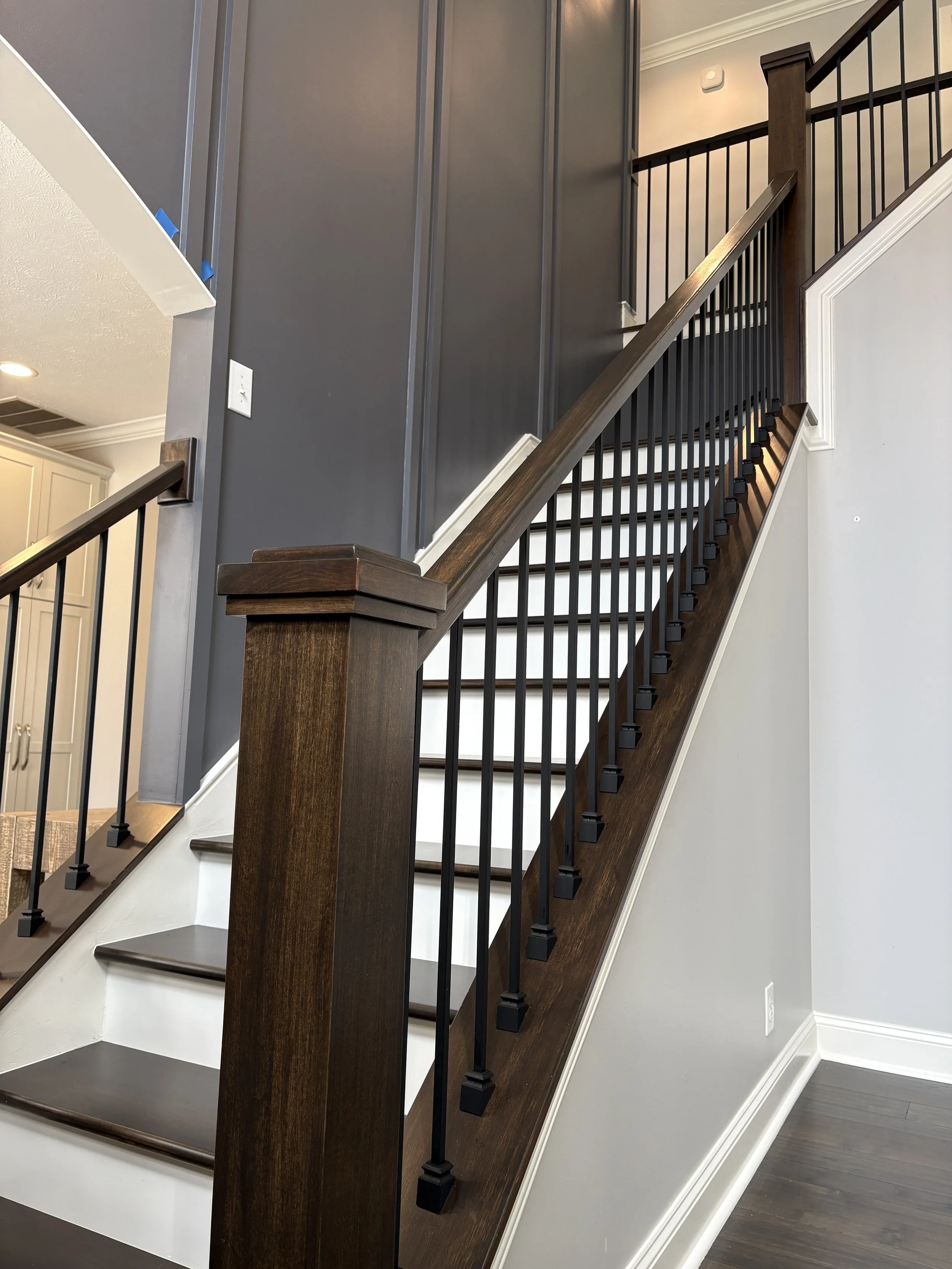 dark stained maple staircase in entryway with white risers and gray accent wall