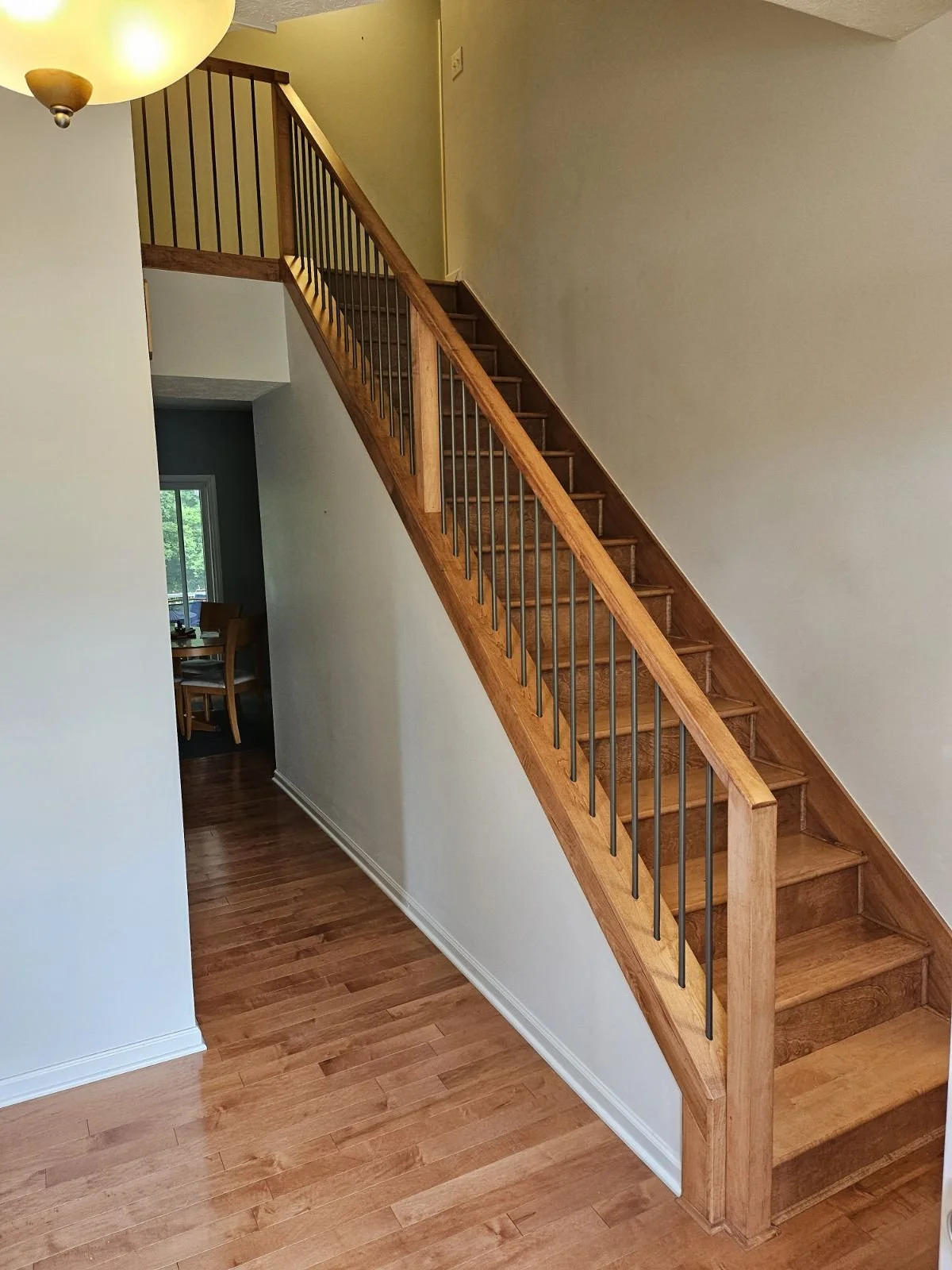 Wooden staircase with black metal balusters ascending from the hardwood floor in a home's interior.