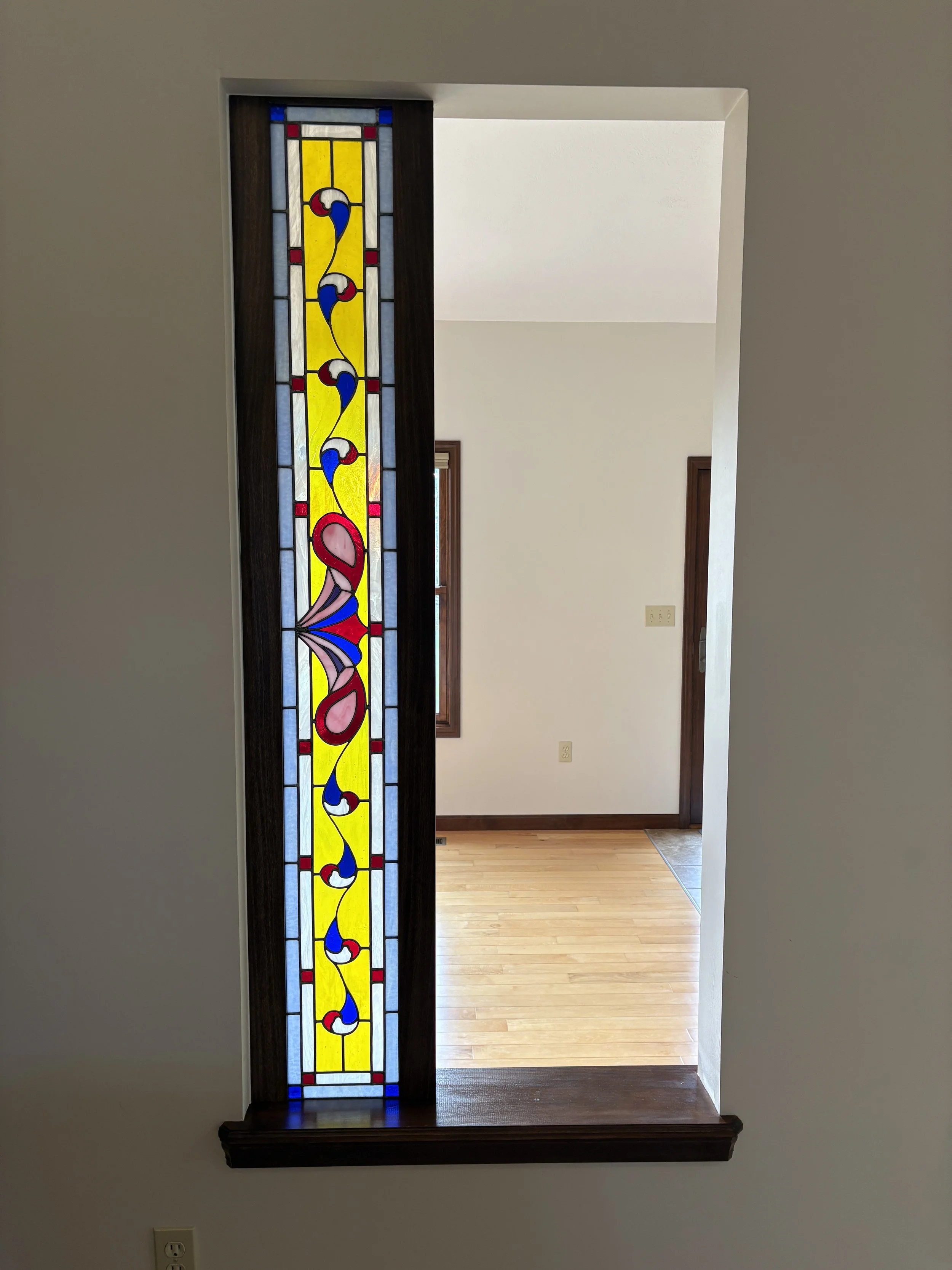 built-in stained wood frame for leaded glass panel inside a house with white walls and hardwood floors