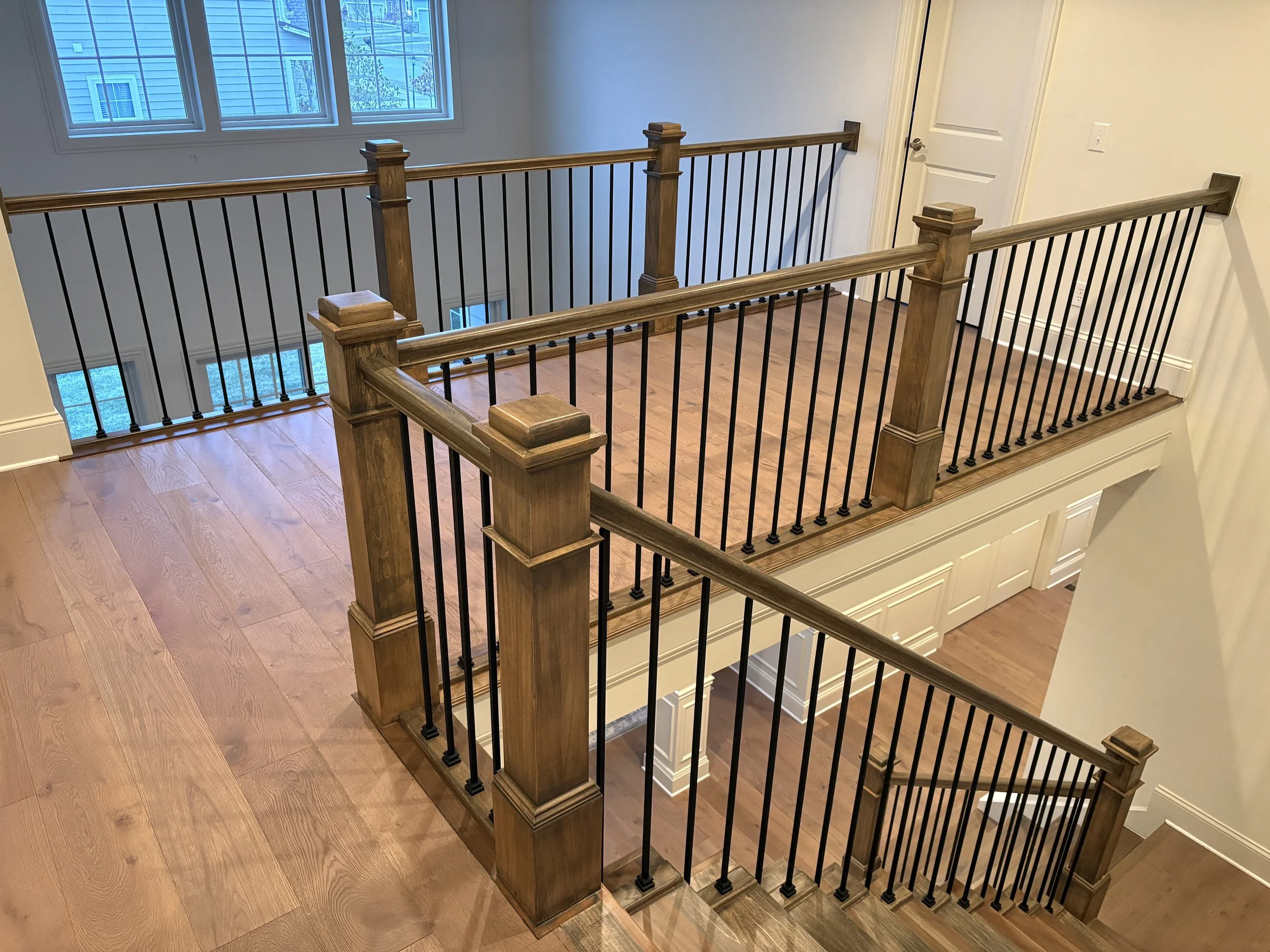 square posts and black iron balusters handrail in a white room