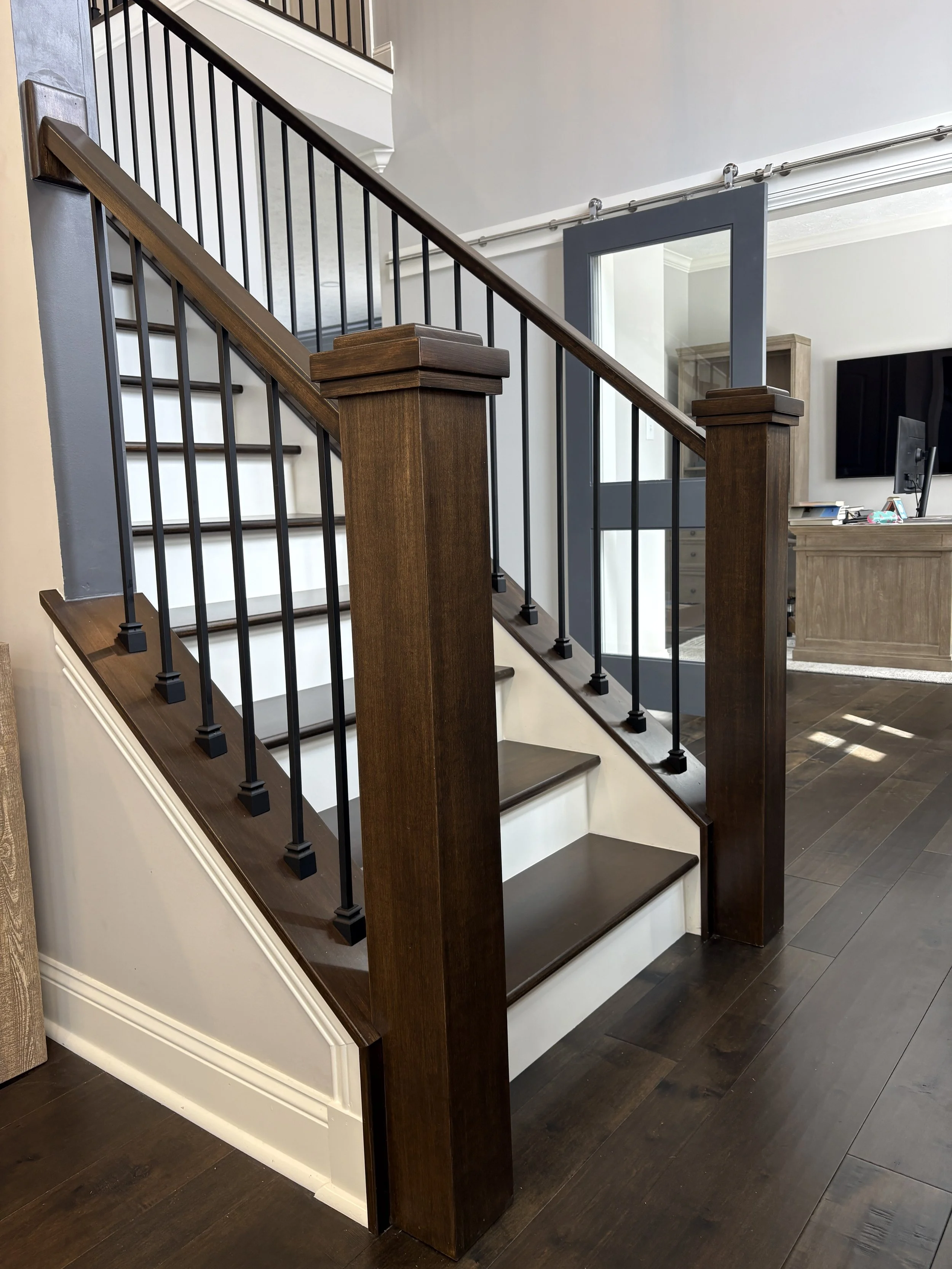 dark stained maple staircase in entryway with white risers and black balusters