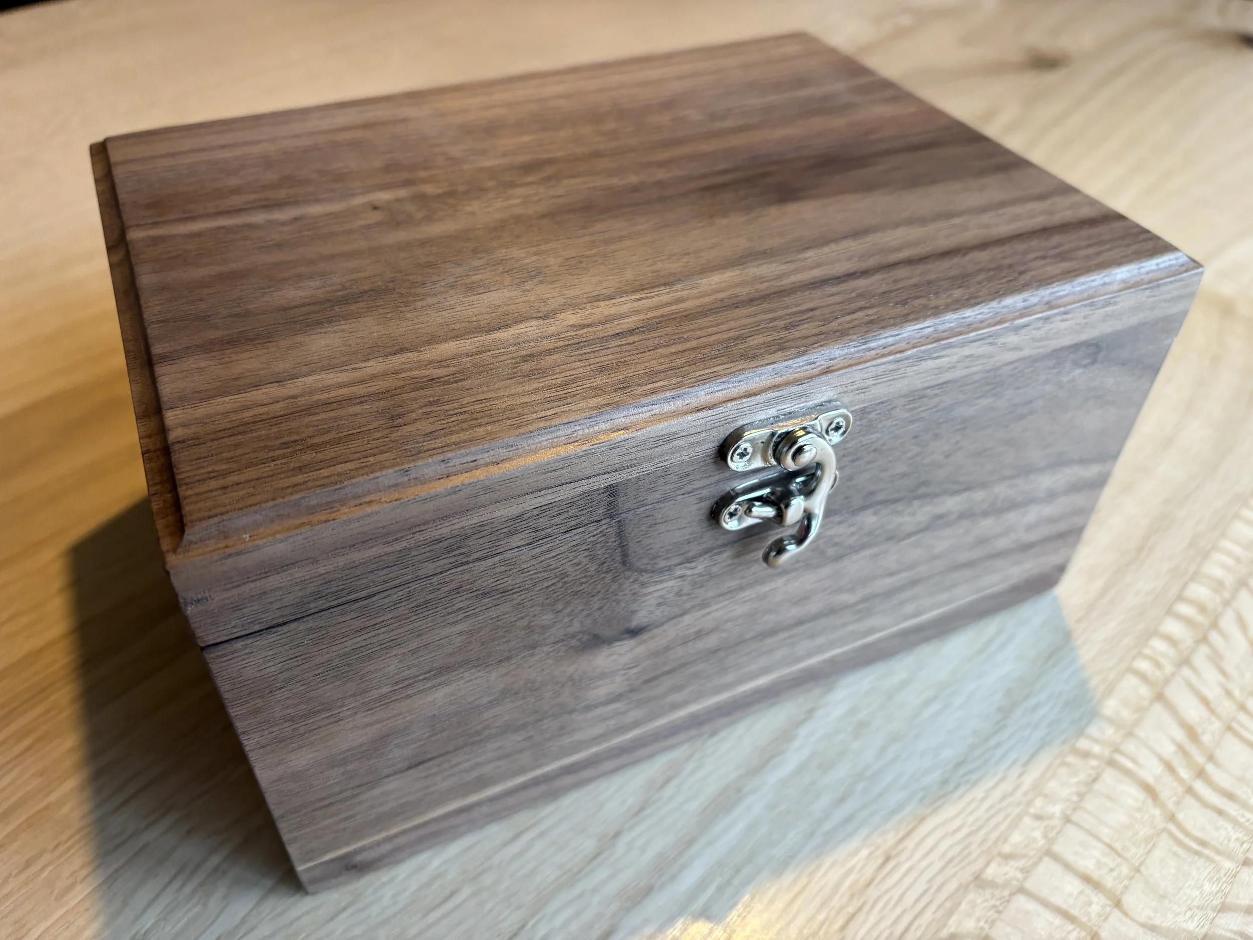 walnut keepsake box on a wooden table with silver ox horn latch