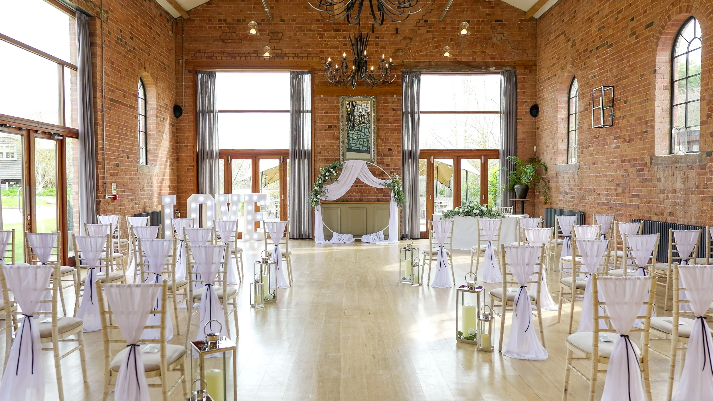 monochrome ceremony decor - white chiffon chair drapes tied with black ribbon and silver lanterns to line the aisle