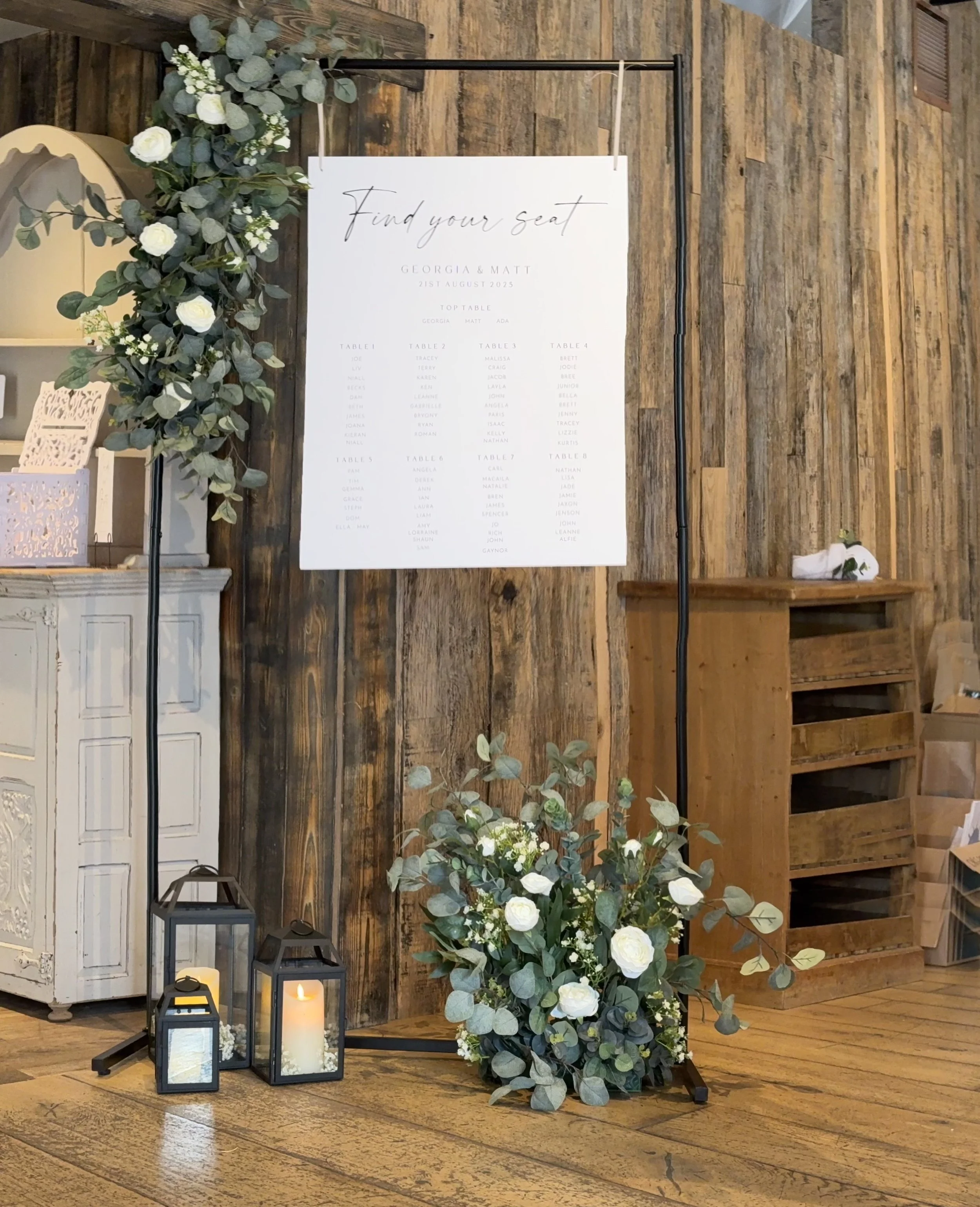 Wedding seating chart display with floral arrangements and candles.