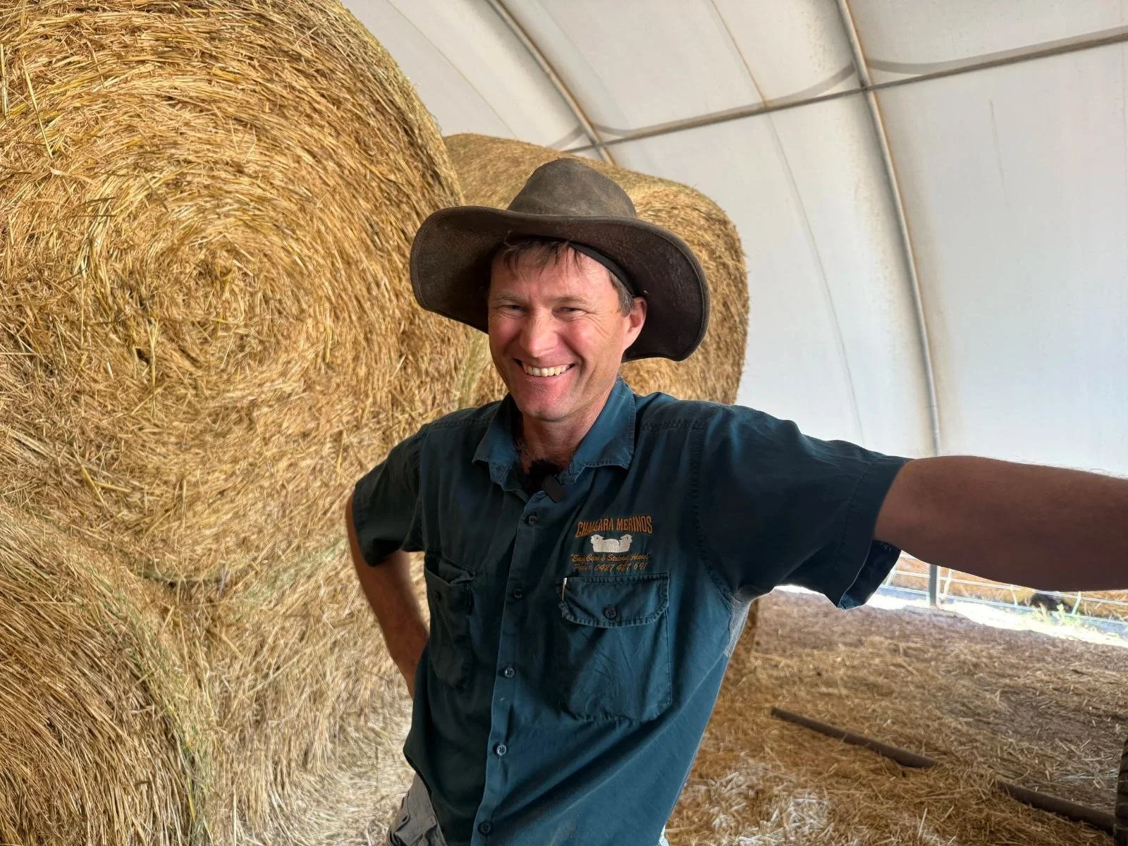 Farmer standing beside round hay bales in a shed at Wilandra, Badgingarra