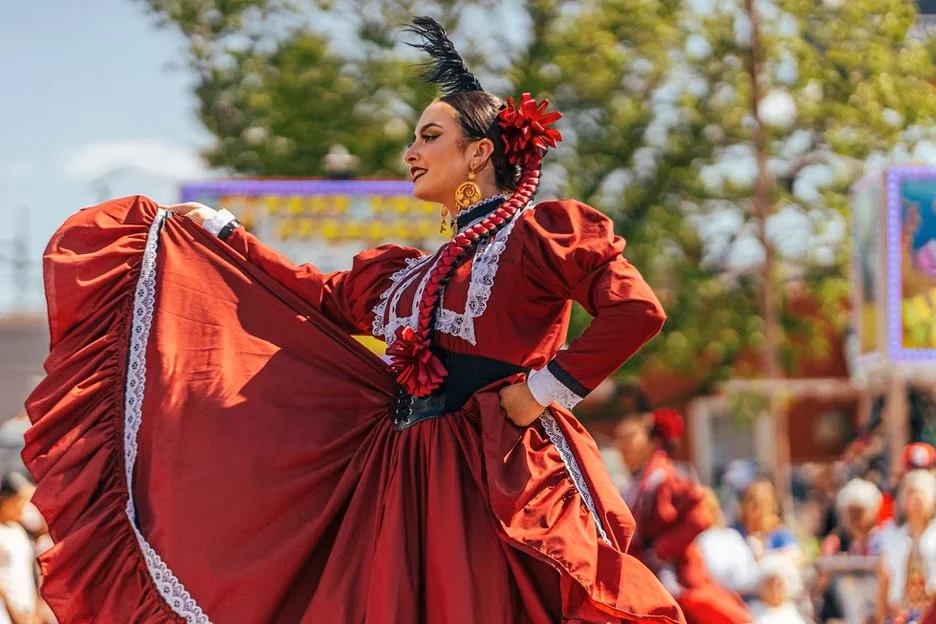 woman in a vibrant red dress joyfully dancing during a lively parade celebration
