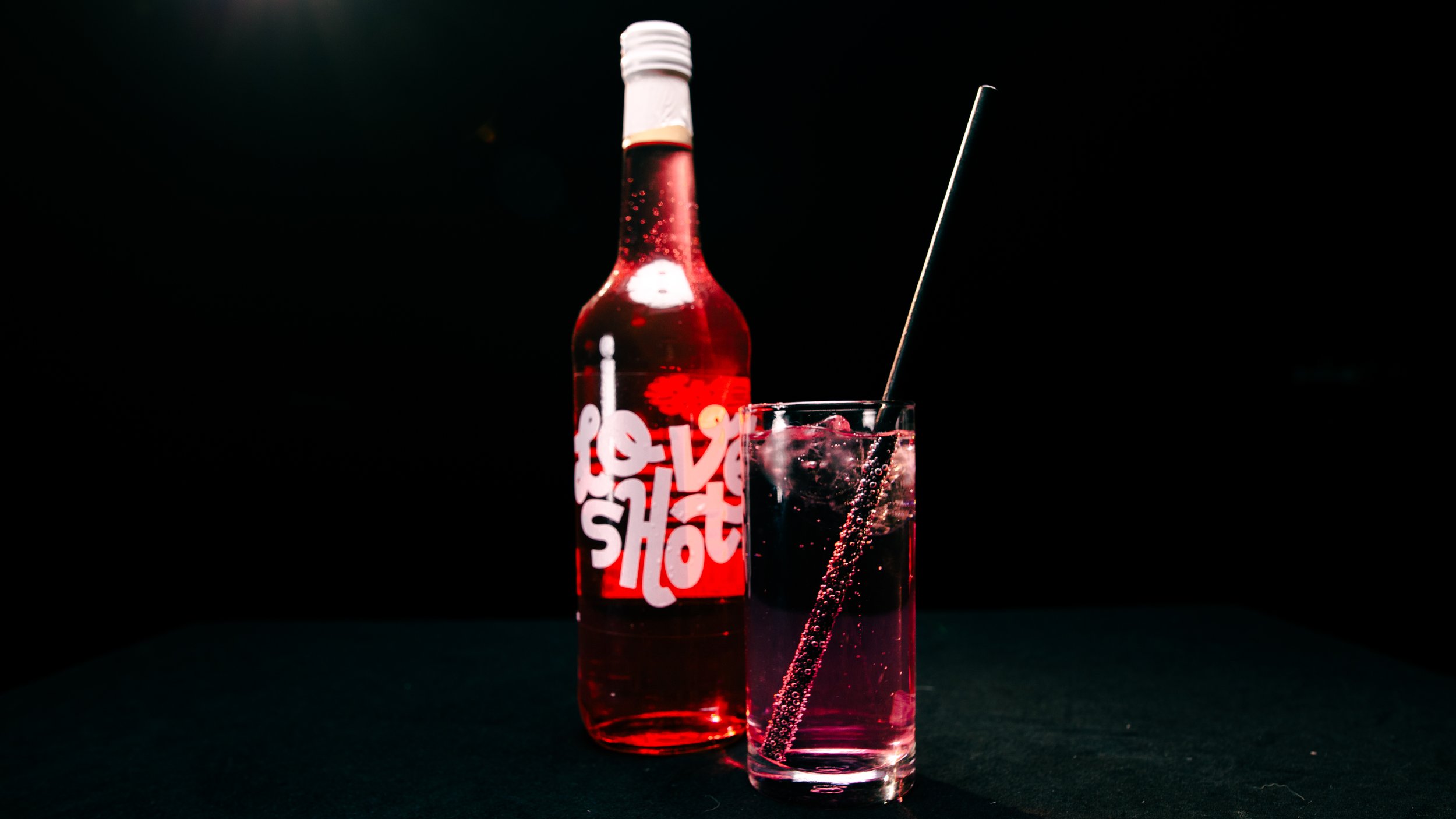 Een fles Love Shot met een Affaire mixdrank in een longdrinkglas