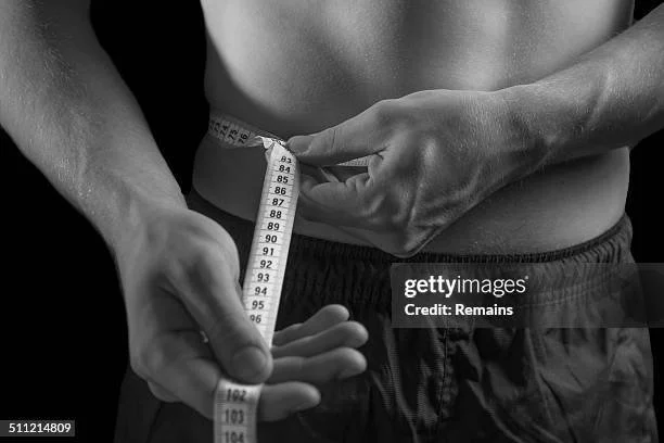 Person measuring their waist with a measuring tape.