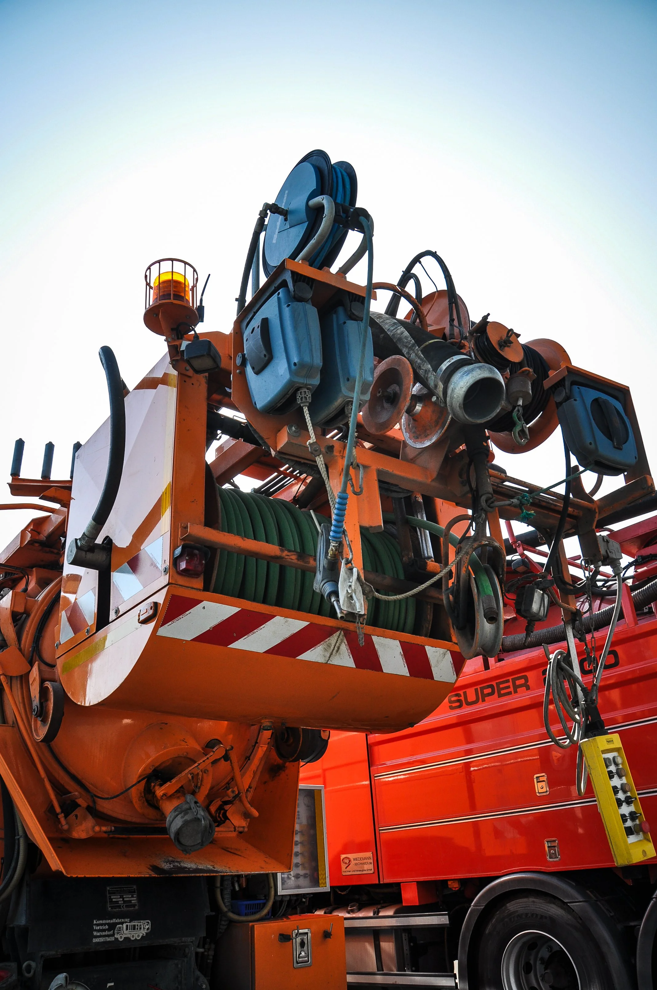 Nahaufnahme eines Kanalreingungsfahrzeugs mit Ausrüstung und Gerätschaften auf dem Dach, darunter Schläuche, Kanalreiniger und technisches Equipment.