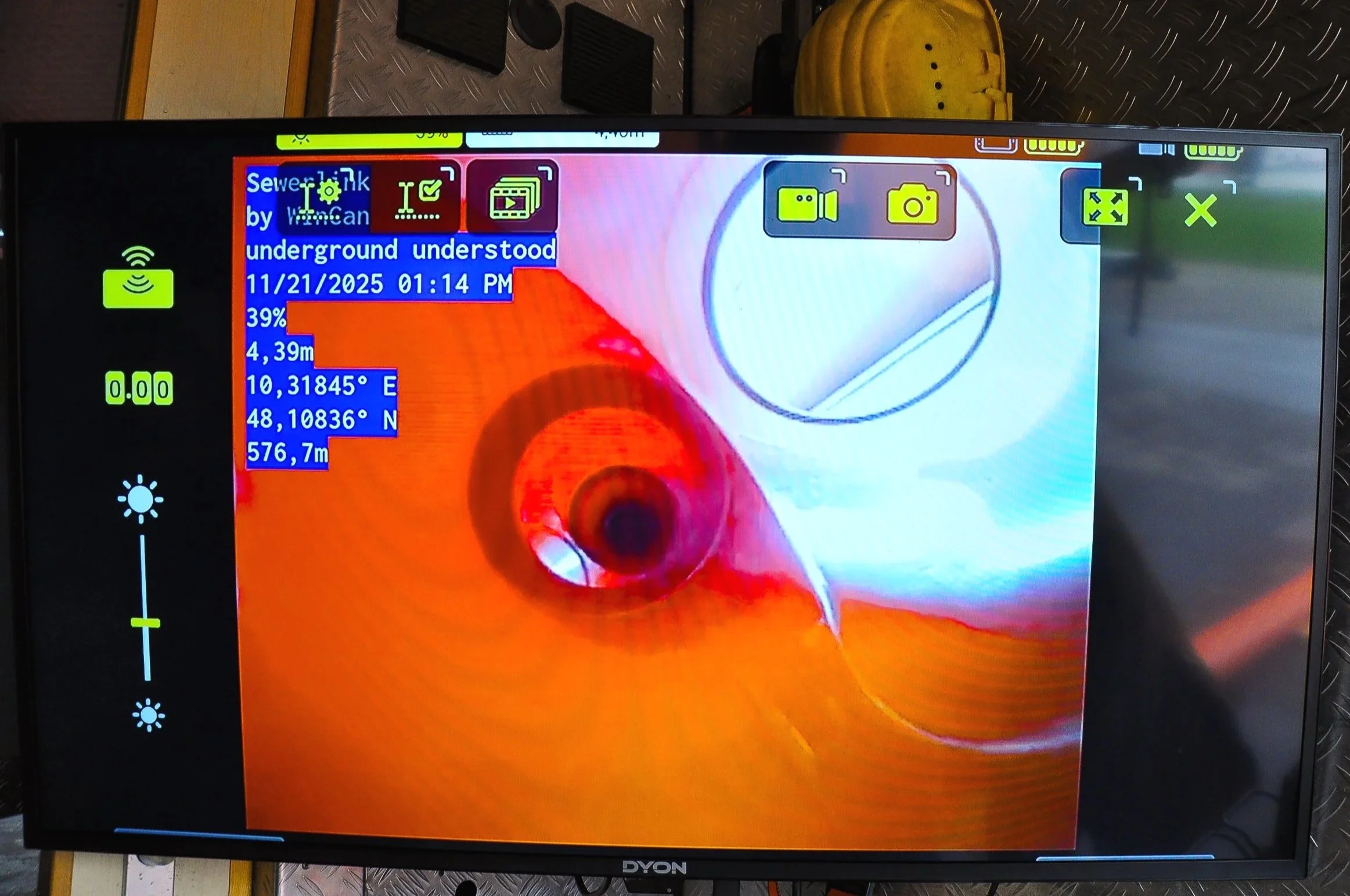 Das Bild zeigt einen Monitor mit einer rötlichen und weißen Innenansicht eines Rohres, wahrscheinlich bei einer Inspektion mit einer Endoskopkamera, inklusive Messdaten und Symbolen auf dem Bildschirm.