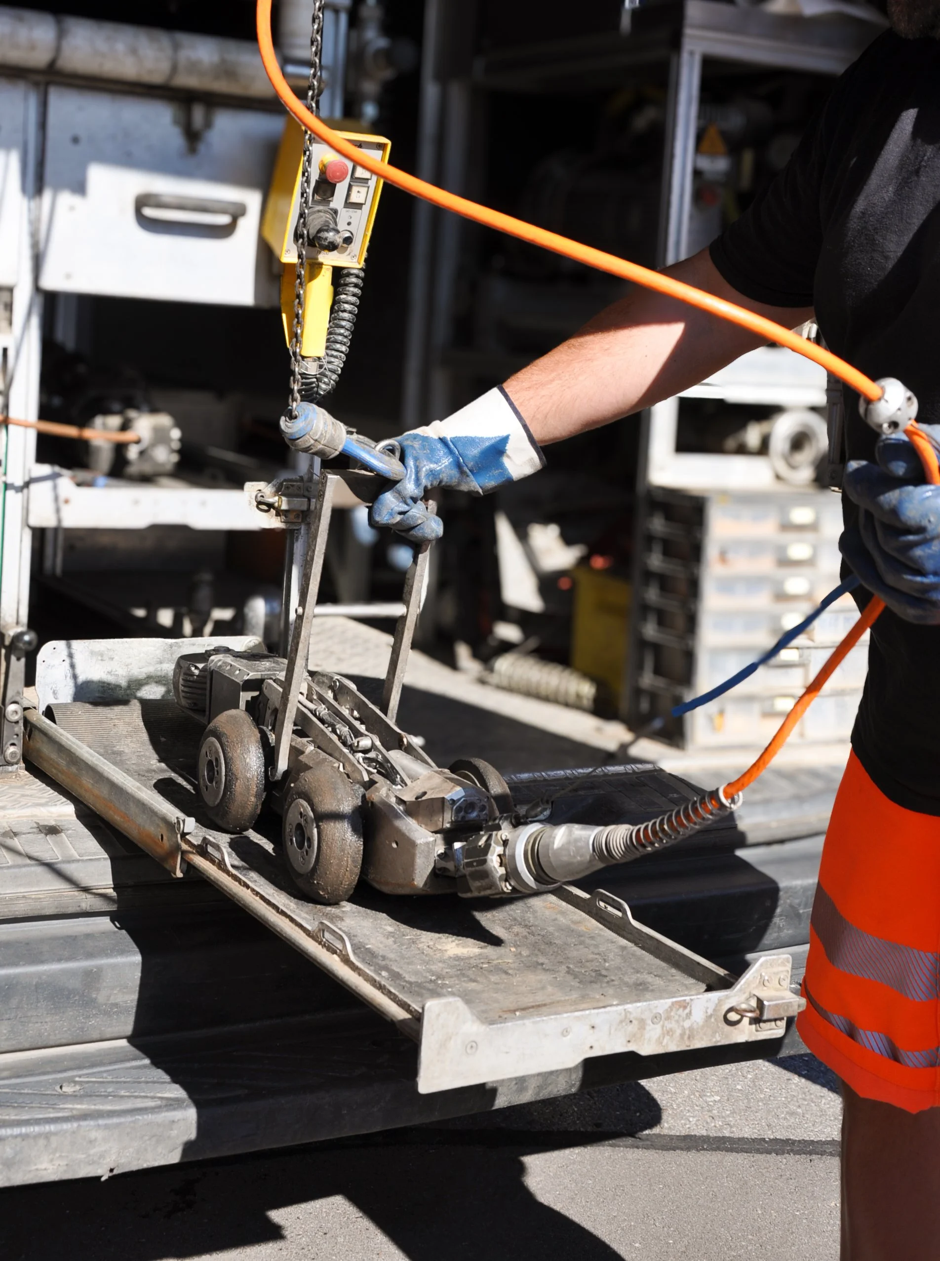 Ein Arbeiter trägt Arbeitshandschuhe und orange Warnweste, während er eine Kanal Kamera für eine TV-Kanalinspektion bedient.