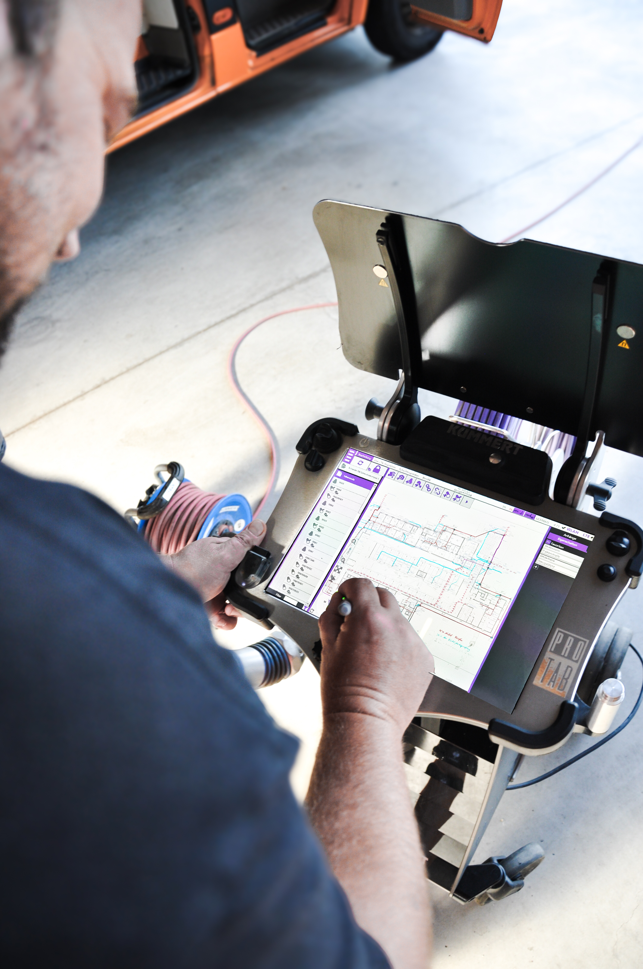 Ein Mensch arbeitet an einem tragbaren Diagnosesystem mit einem Tablet, das einen elektrischen Schaltplan anzeigt, in einer Werkstatt.