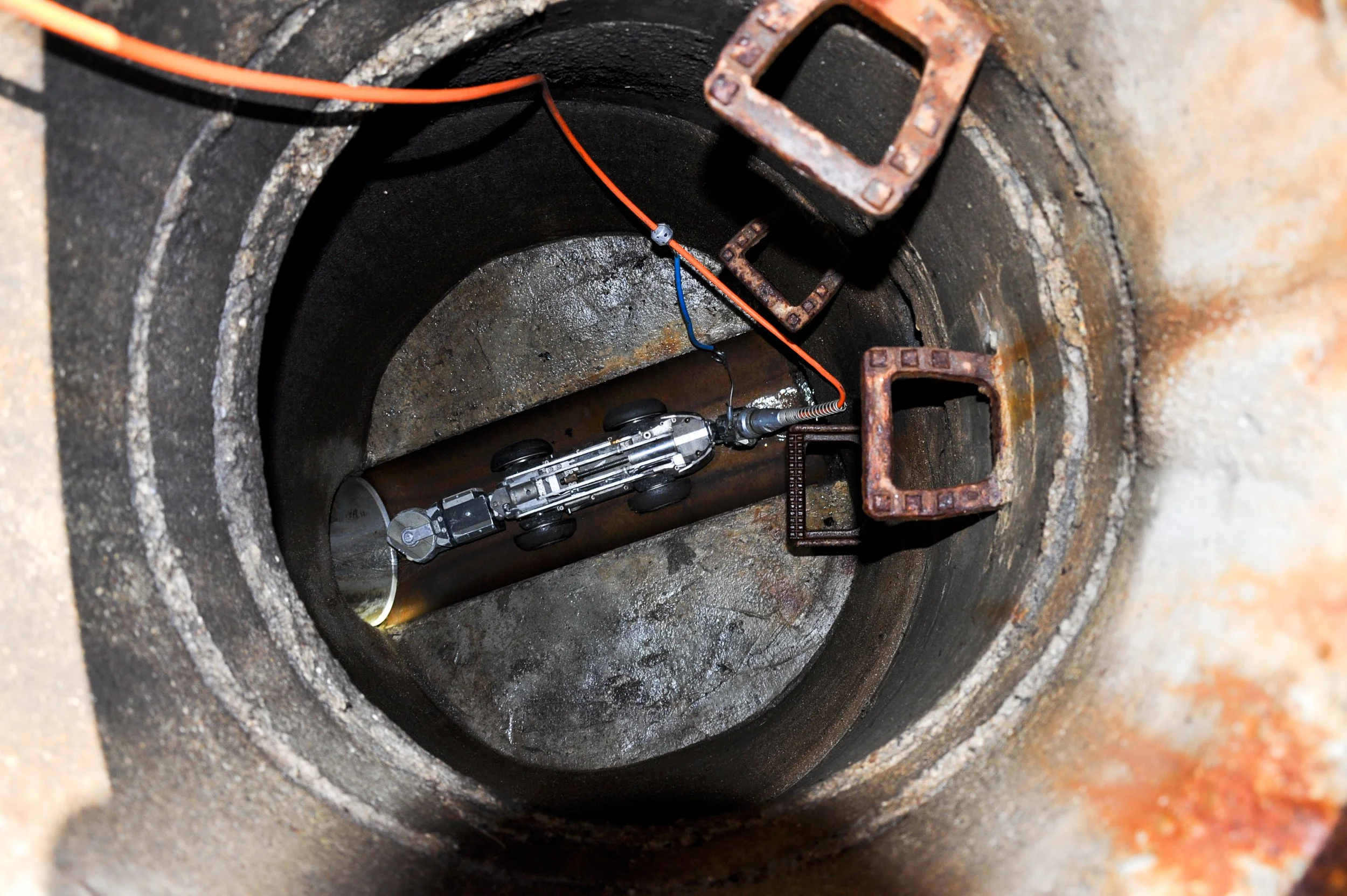 Ein Rohr mit einem kleinen Modellauto darin, das in einem Schacht liegt, mit einigen Kabeln und Metallbefestigungen.