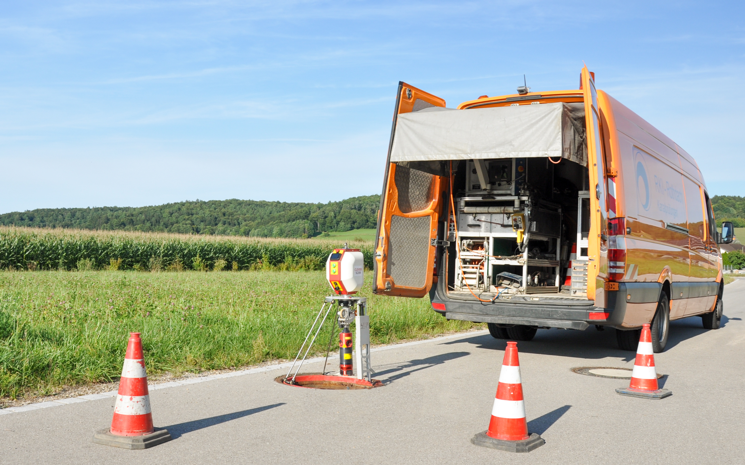 Mobile Schachtinspektion auf einer Landstraße mit Verkehrshütchen, ausgestattet mit technischem Gerät für die Inspektion von Kanalschächten.