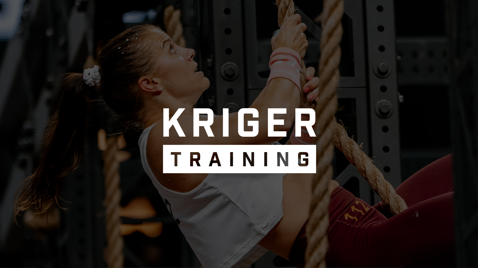 A woman with a ponytail is doing a workout hanging from a rope in a gym. The text 'Kriger Training' is overlaid on the image.