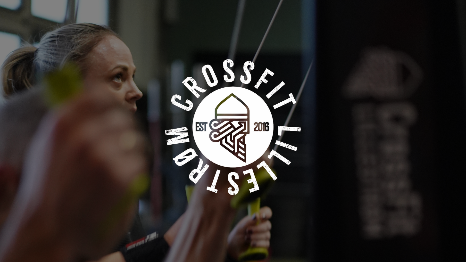 A woman at a CrossFit gym lifting weights with the CrossFit logo overlayed on the image.