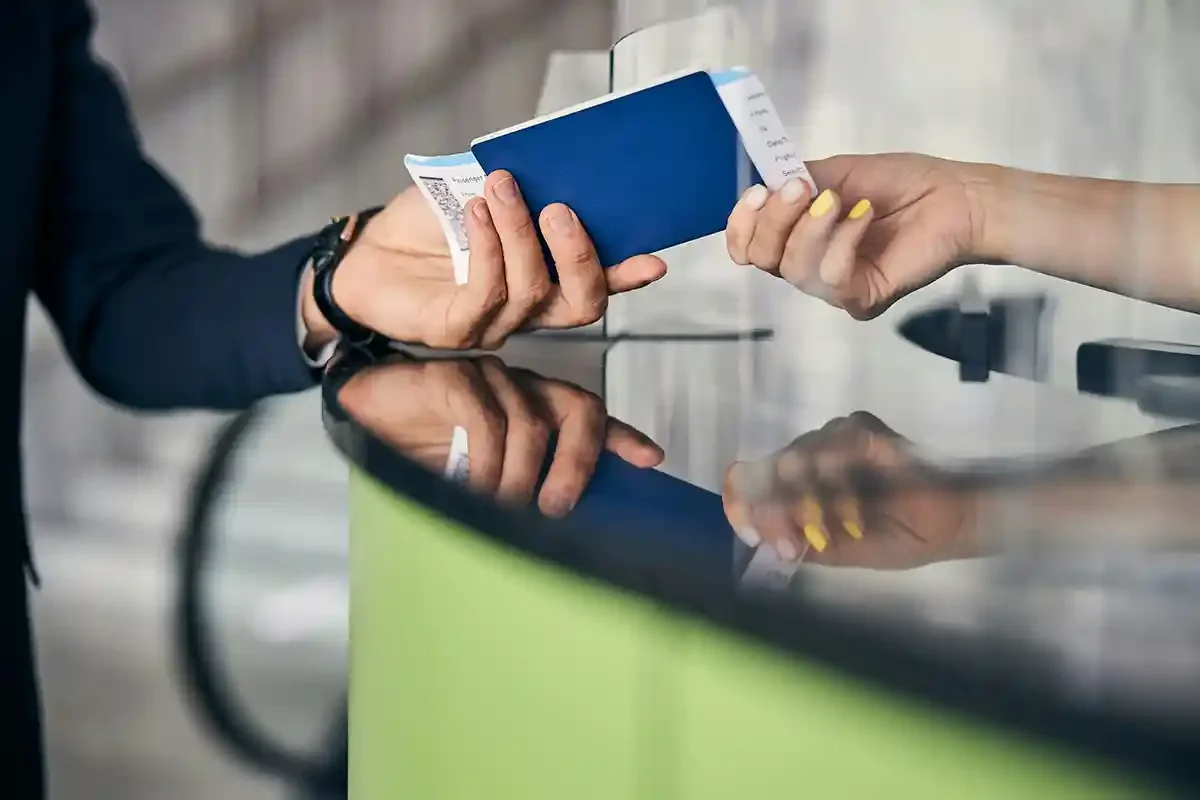 Passport and boarding pass being handed over at an airport check-in desk, representing the UK customs border