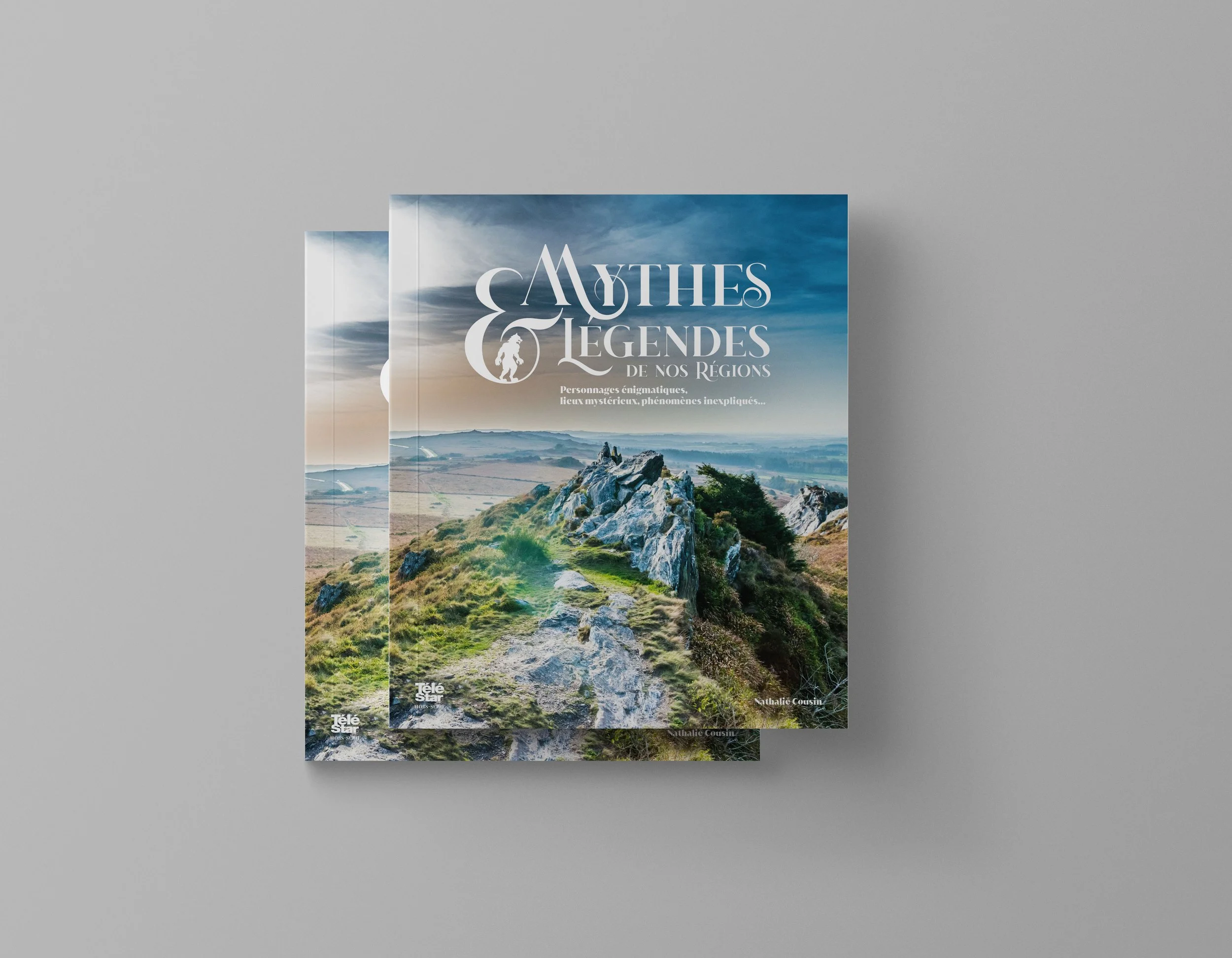 Livres empilés présentant une couverture avec une photographie d'un paysage 
rocheux et verdoyant sous un ciel nuageux, le thème des mythes et légendes régionales.