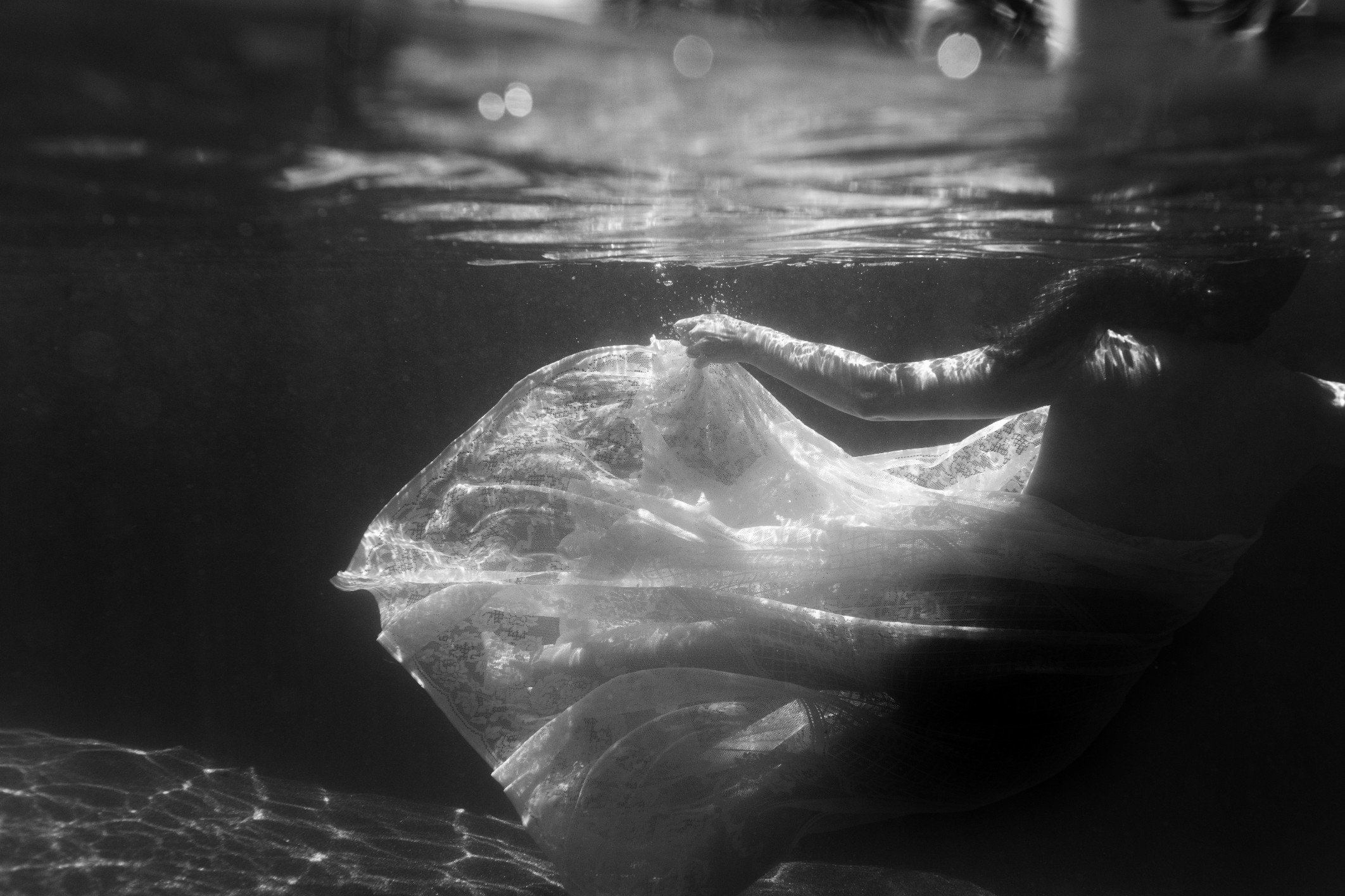 Underwater scene with a woman holding up a lace cloth