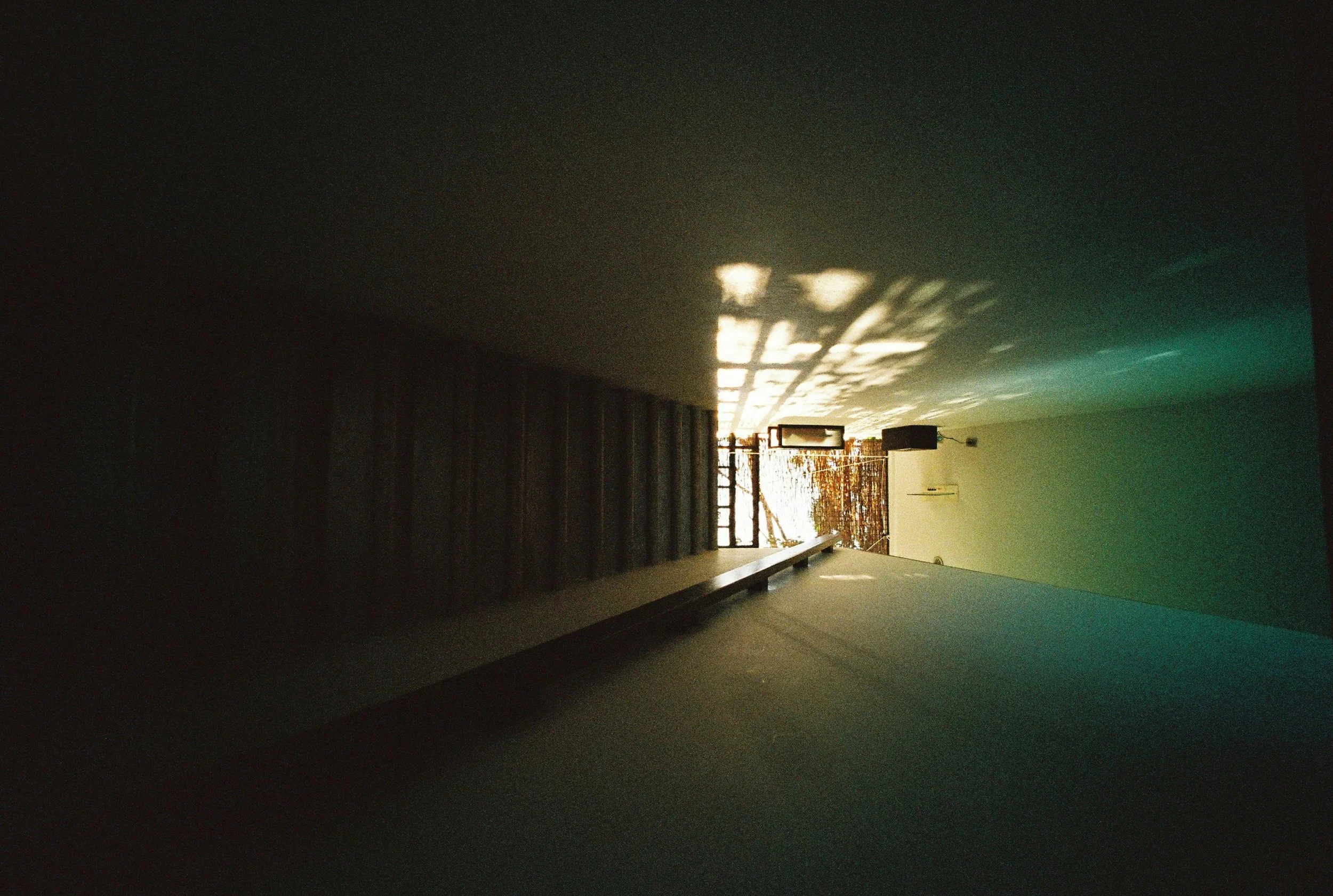 Spazio interno in penombra con luce in fondo, attesa e riflessione