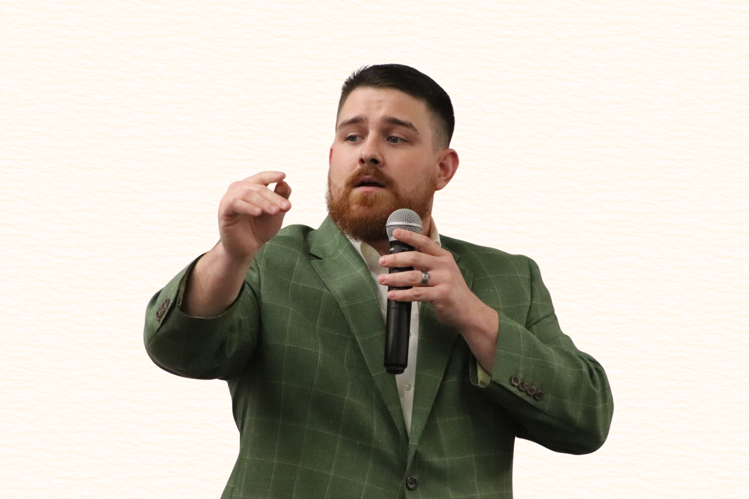 Man in green plaid suit speaking into a microphone