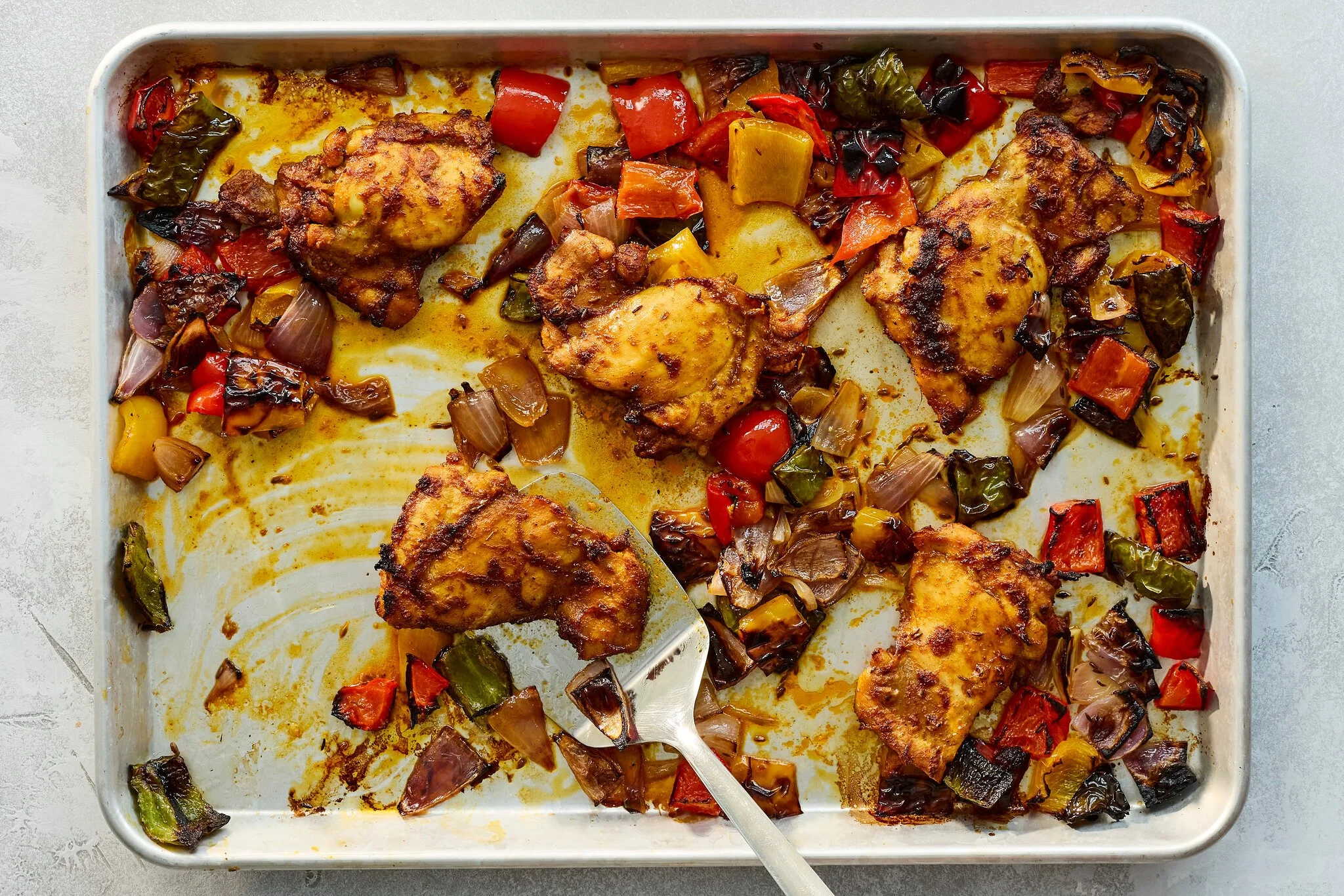baked chicken thighs in a pan with roasted vegetables