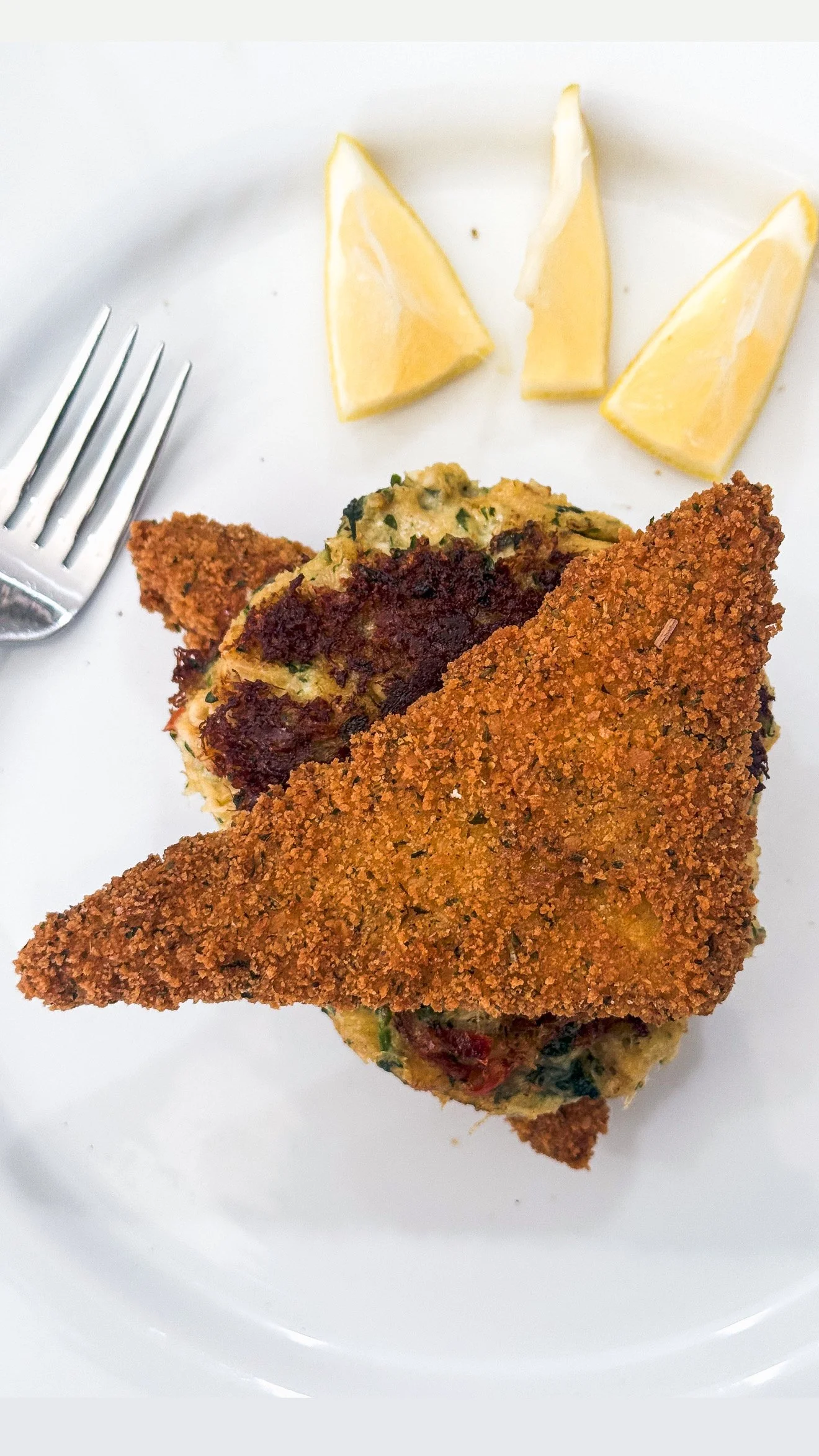 crab cake and deep fried grits with lemon wedges on a plate