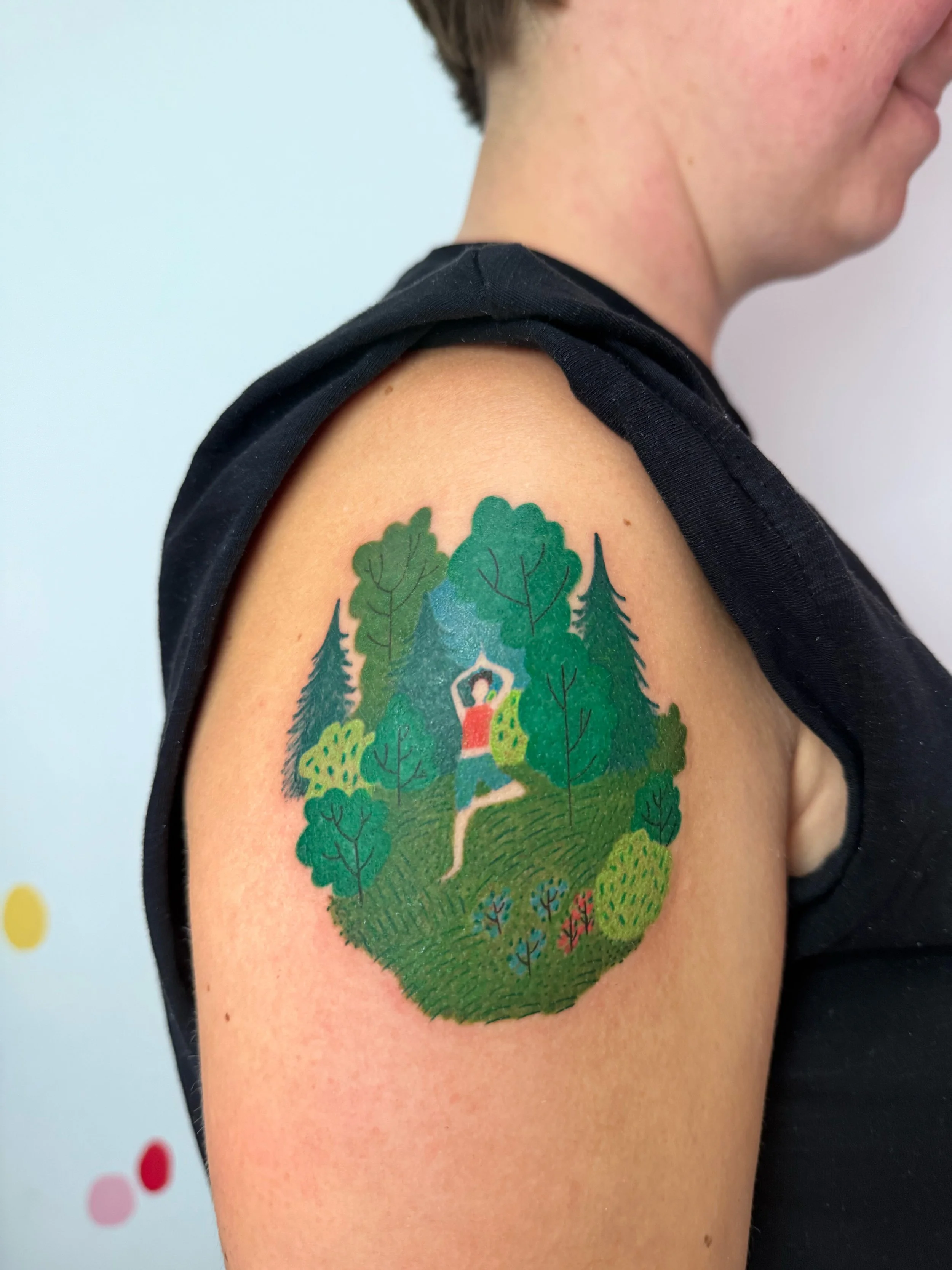 a shoulder tattoo of a woman standing in a tree yoga pose in the middle of the forest