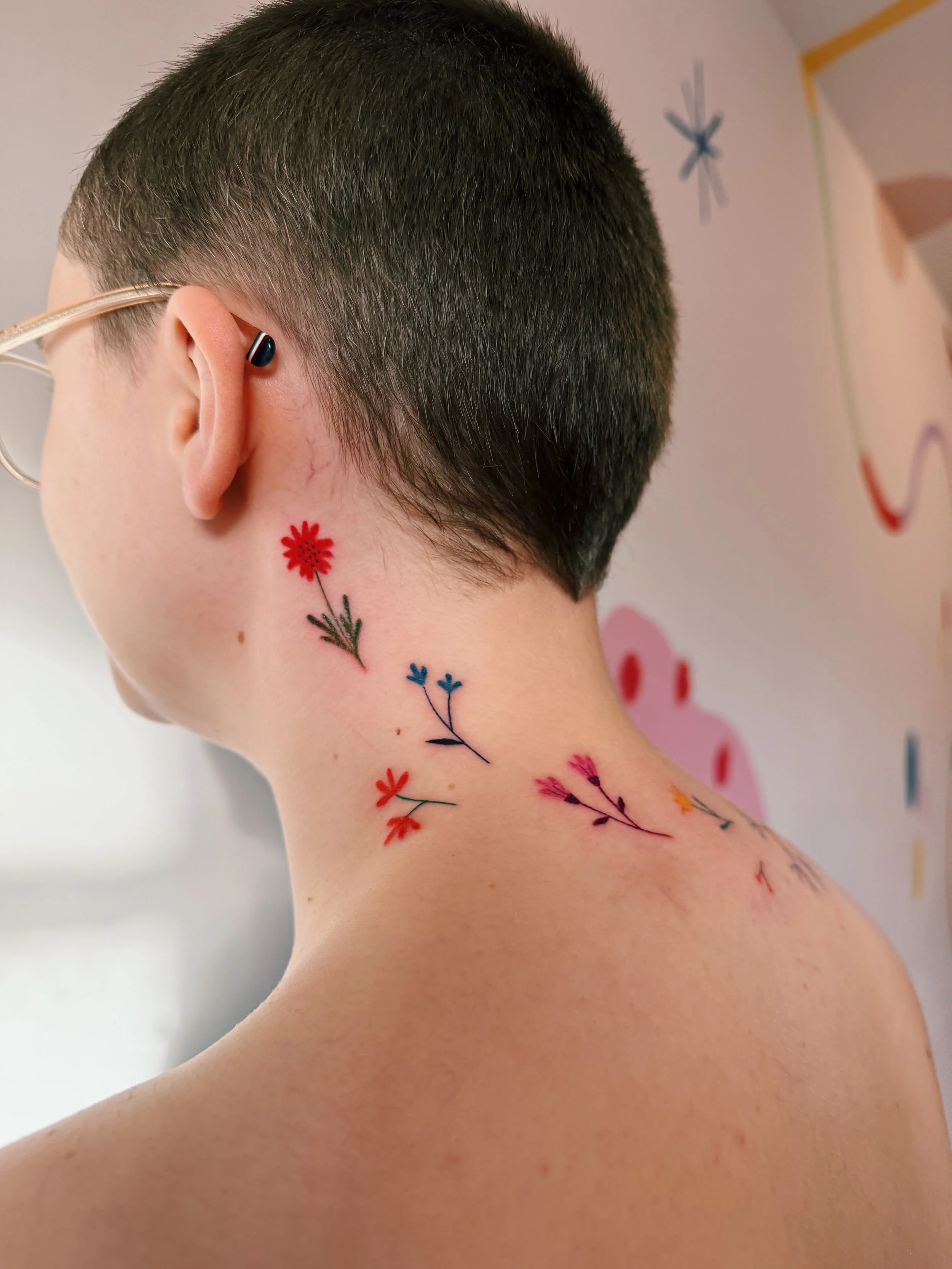 a colorful tattoo on the neck of freehanded flowers