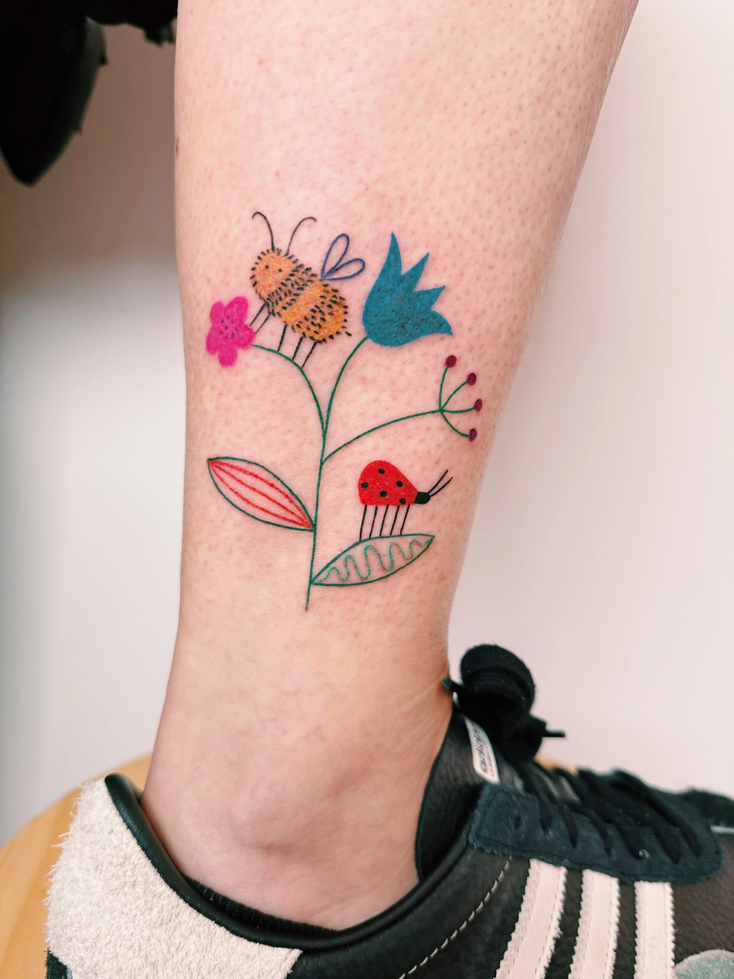 a colorful freehanded tattoo with flowers and berries