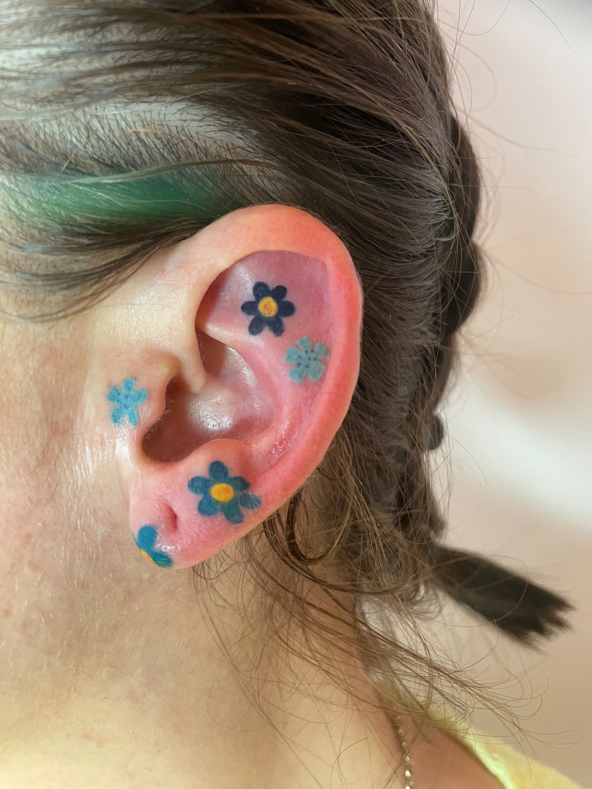 colorful floral tattoos on an ear