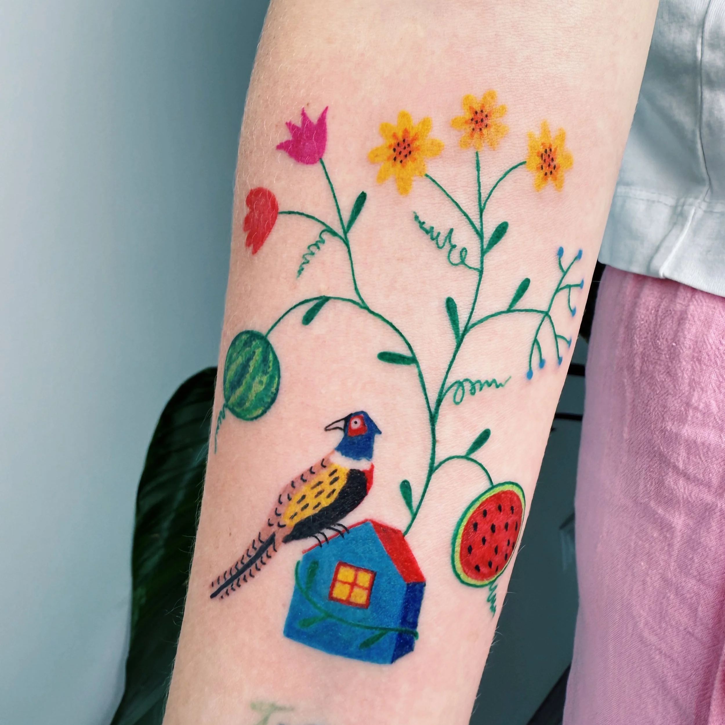a tattoo of a pheasant sitting on a house with flowers and watermelons