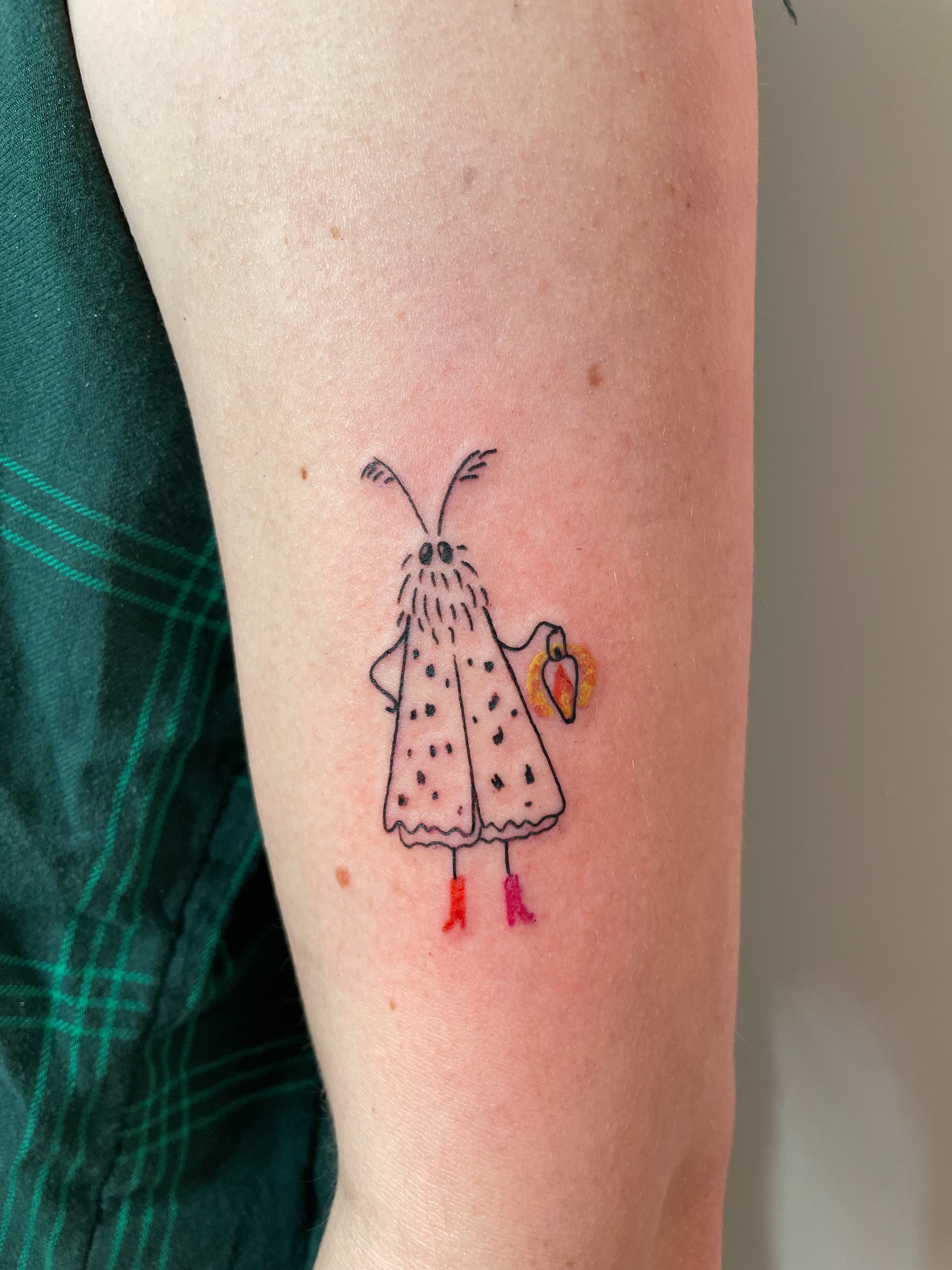 a custom tattoo of a cute moth wearing colorful boots holding a gas lamp