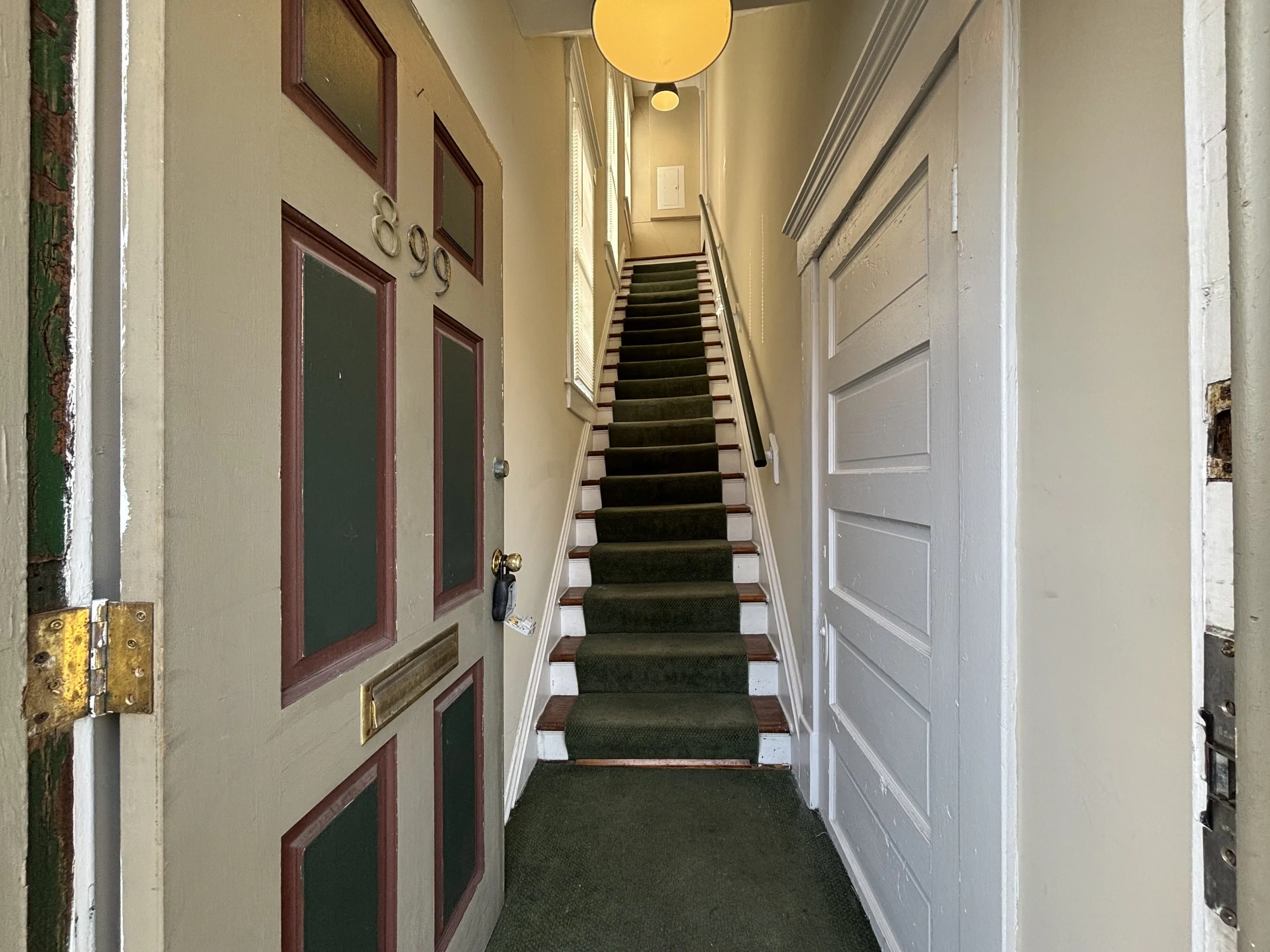Front door of a house with stairs leading to the upper level visible through the open doorway.
