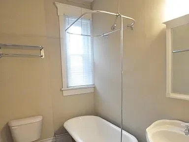 Bathroom with a clawfoot bathtub, a window with blinds, a wall-mounted mirror cabinet, and a towel rack.