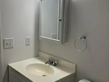 Bathroom vanity with sink, mirror, towel ring, and electrical outlets