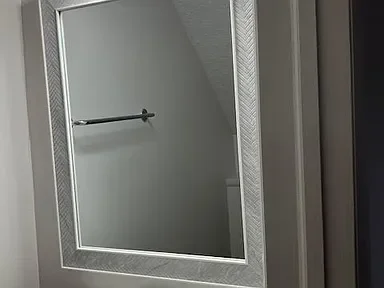 Bathroom mirror reflecting a white wall and a towel rack