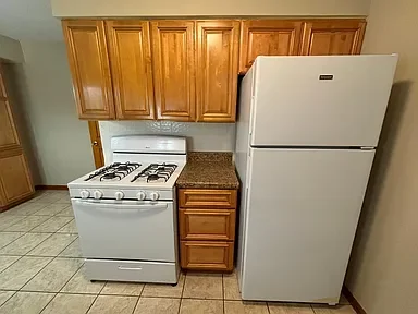 Kitchen with wooden cabinets, a white gas stove, a granite countertop, and a large white refrigerator.