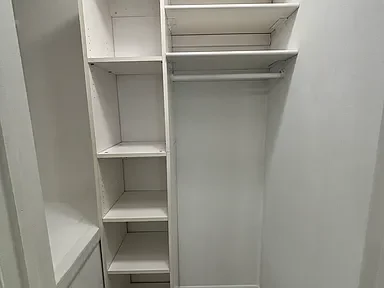 Empty white closet with built-in shelves and hanging rod