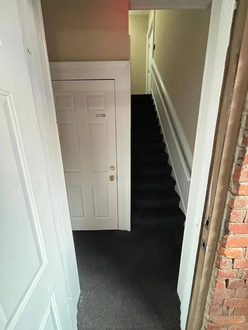 Entryway with a staircase, front door, and exposed brick wall.