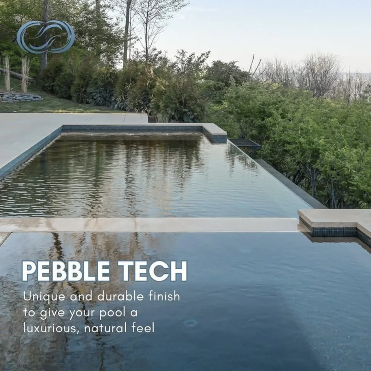 A swimming pool with a water feature and surrounded by lush greenery and trees, with the sky visible in the background.