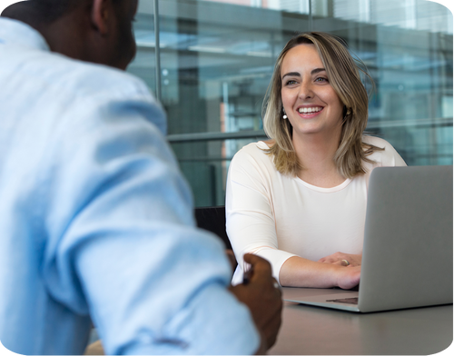 A woman smiling during a conversation with a man in a modern office setting