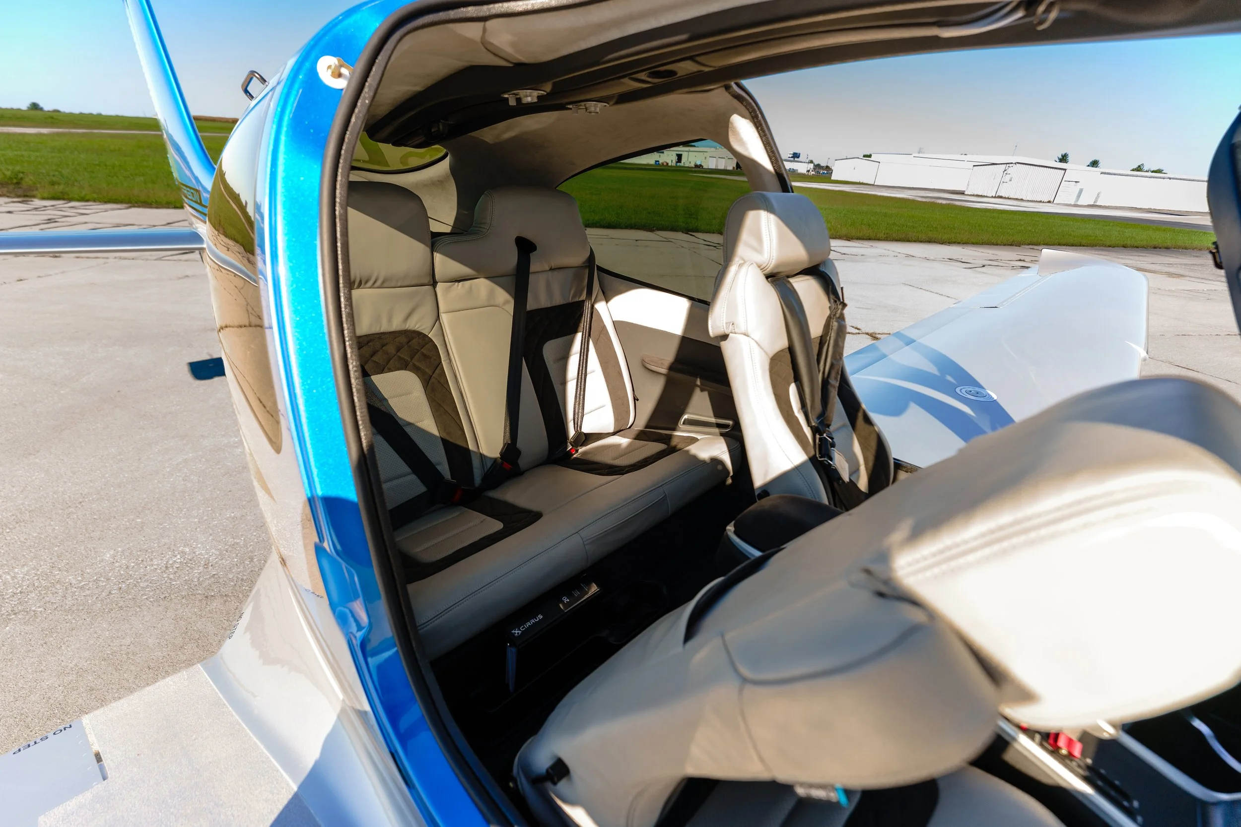 Interior view of a Cirrus aircraft showing the passenger seating and cabin through an open door.