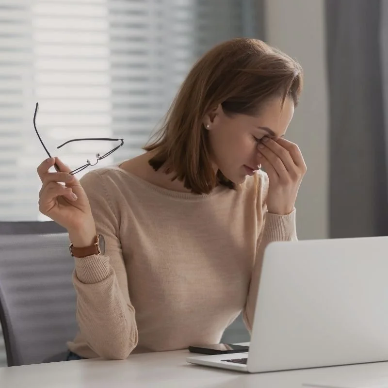 Frau sitzt müde an ihrem Laptop