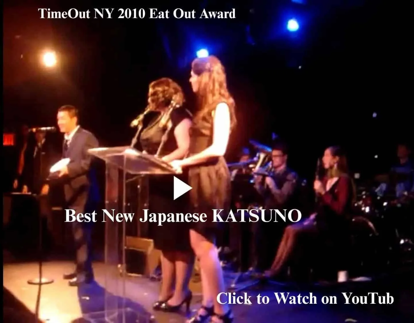 TIME OUT NEW YORK 2010 EAT OUT AWARD Best New Japanese KATSUNO. Photo of an awards ceremony stage where two women and the chef are holding a microphone and raising the award trophy. Click to watch on YouTube.