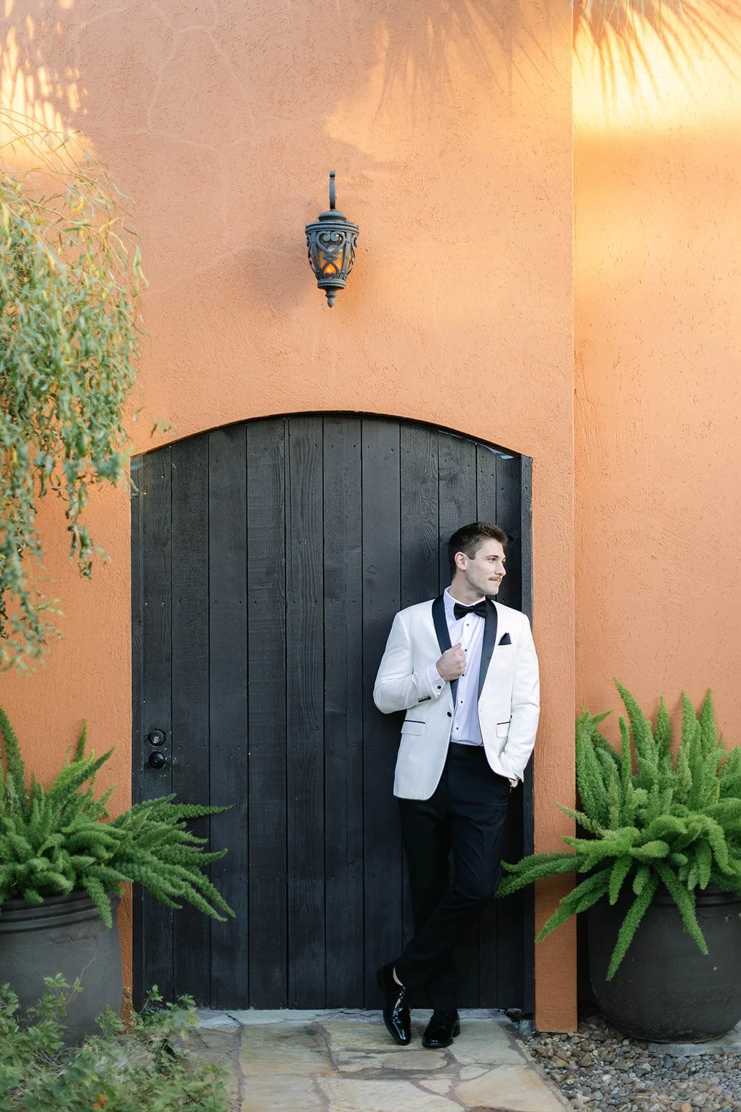 Groom wearing tuxedo in front of wooden door in Houston TX